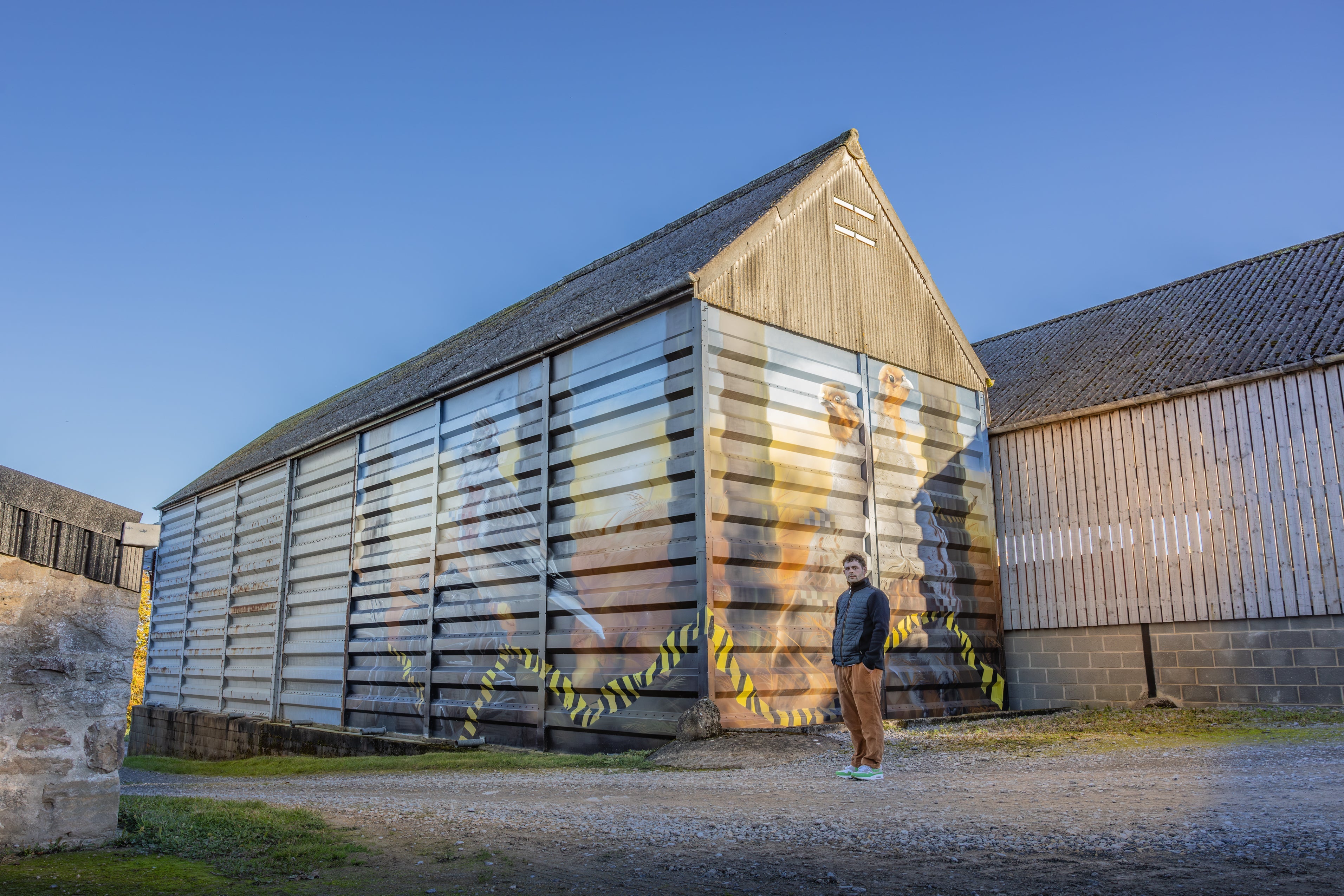 Street art mural on countryside barn with caution tape design