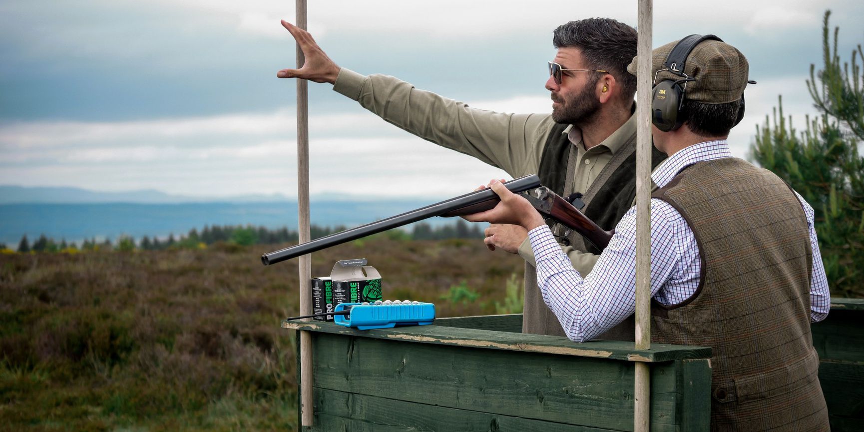 Man holding black double-barreled shotgun with wooden stock at Gleneagles grouse shoot