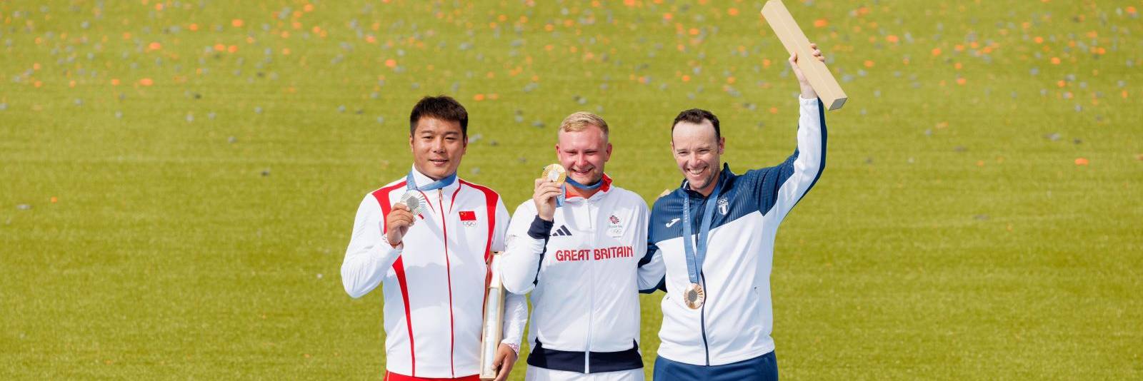 Olympic trap gold medalist Nathan Hales on podium with medal and baton