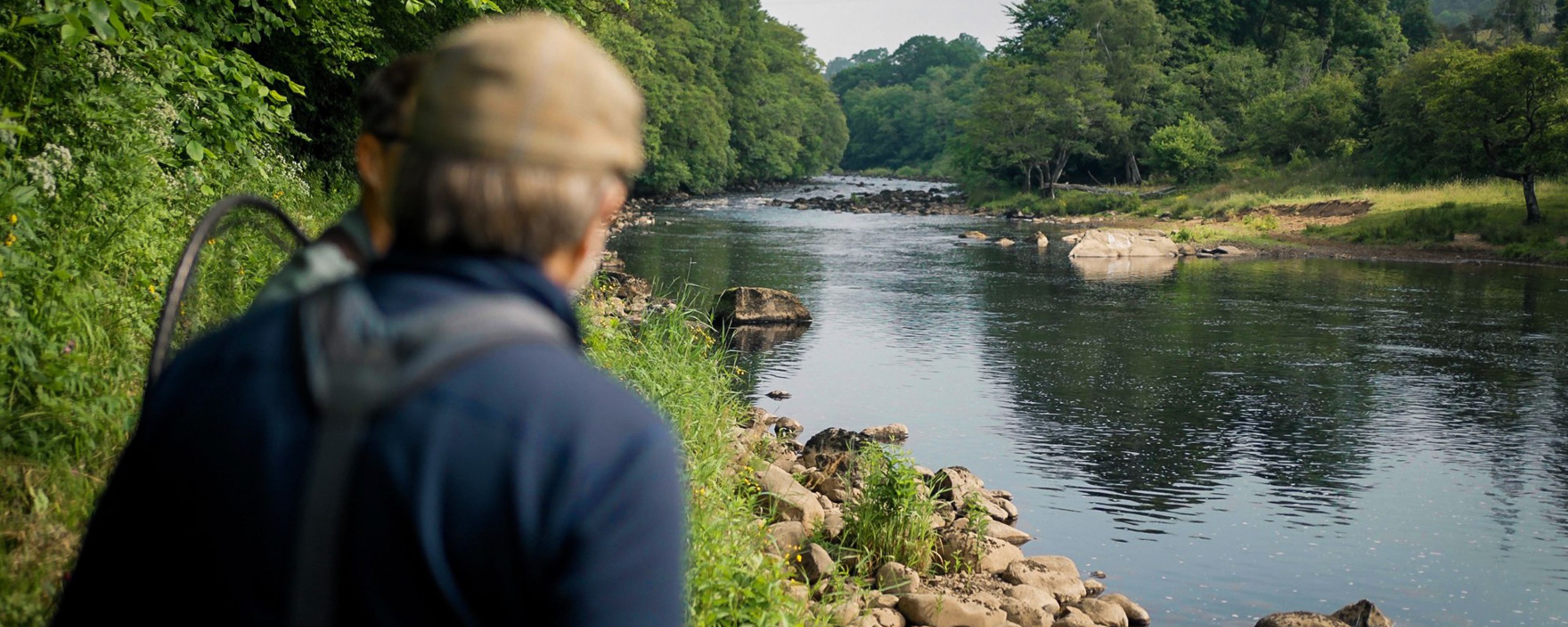 Fly fisher James Stokoe in beige cap and blue jacket on River Tyne bank