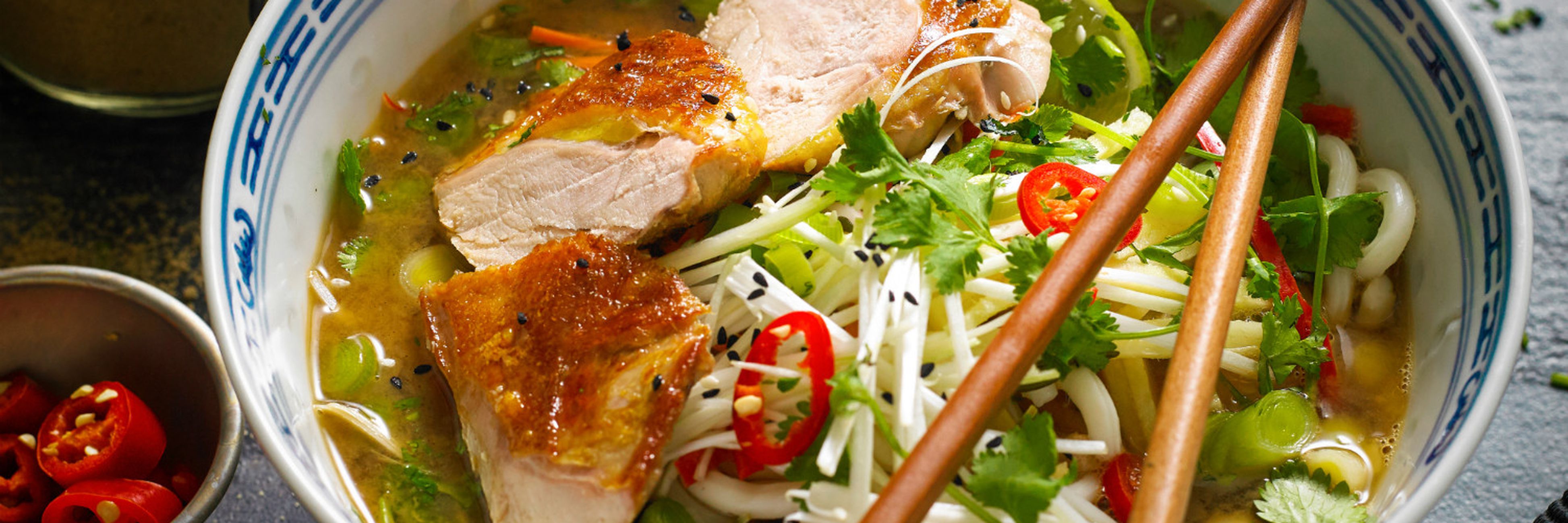 White ceramic bowl of slow roast pheasant ramen with chicken and chili