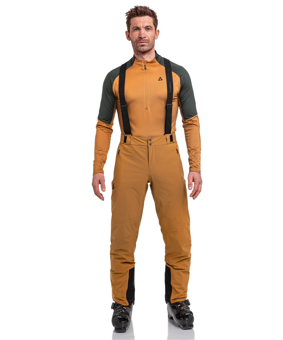 Man wearing men’s pine caramel ski pants with black suspenders and a mustard-yellow and dark green
