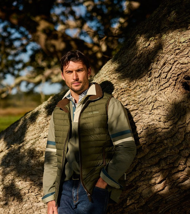 Man standing next to a large tree in an outdoor setting
