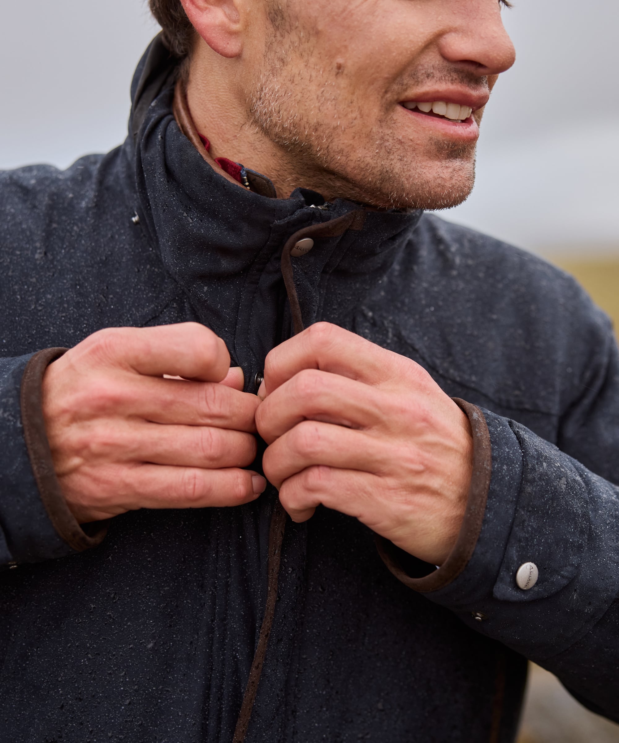 Man adjusting the hood of a dark coat outdoors