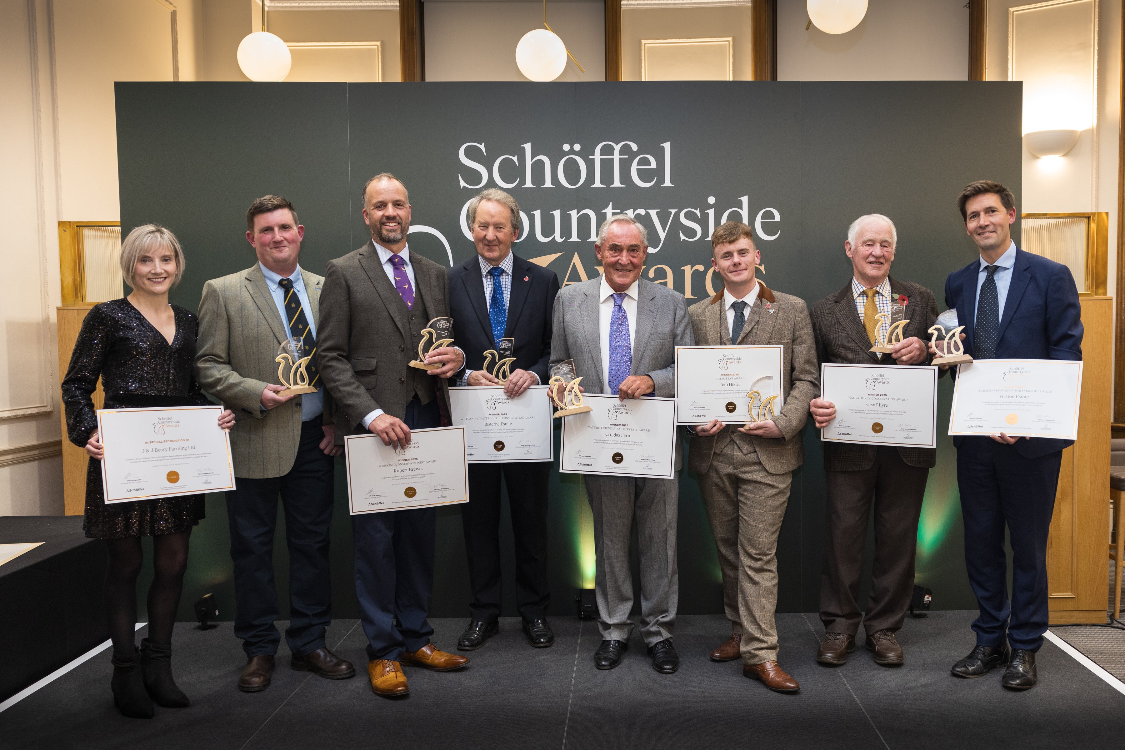 Group of people holding certificates in a formal setting with 'Schöffel Countryside' branding.