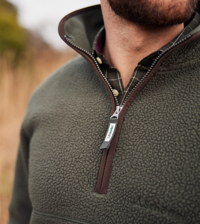 Close-up of a man wearing a woodland green textured fleece quarter-zip with a dark brown