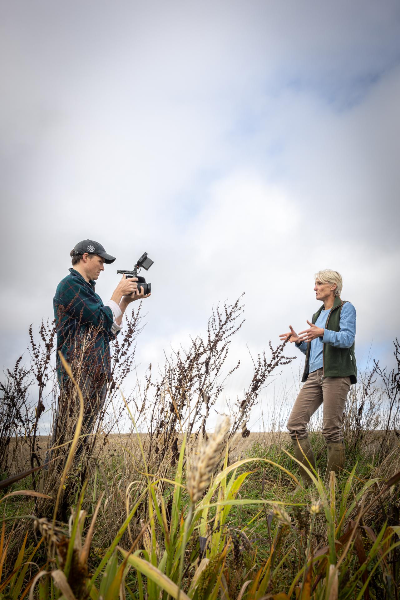 Two people in a field with one holding a camera