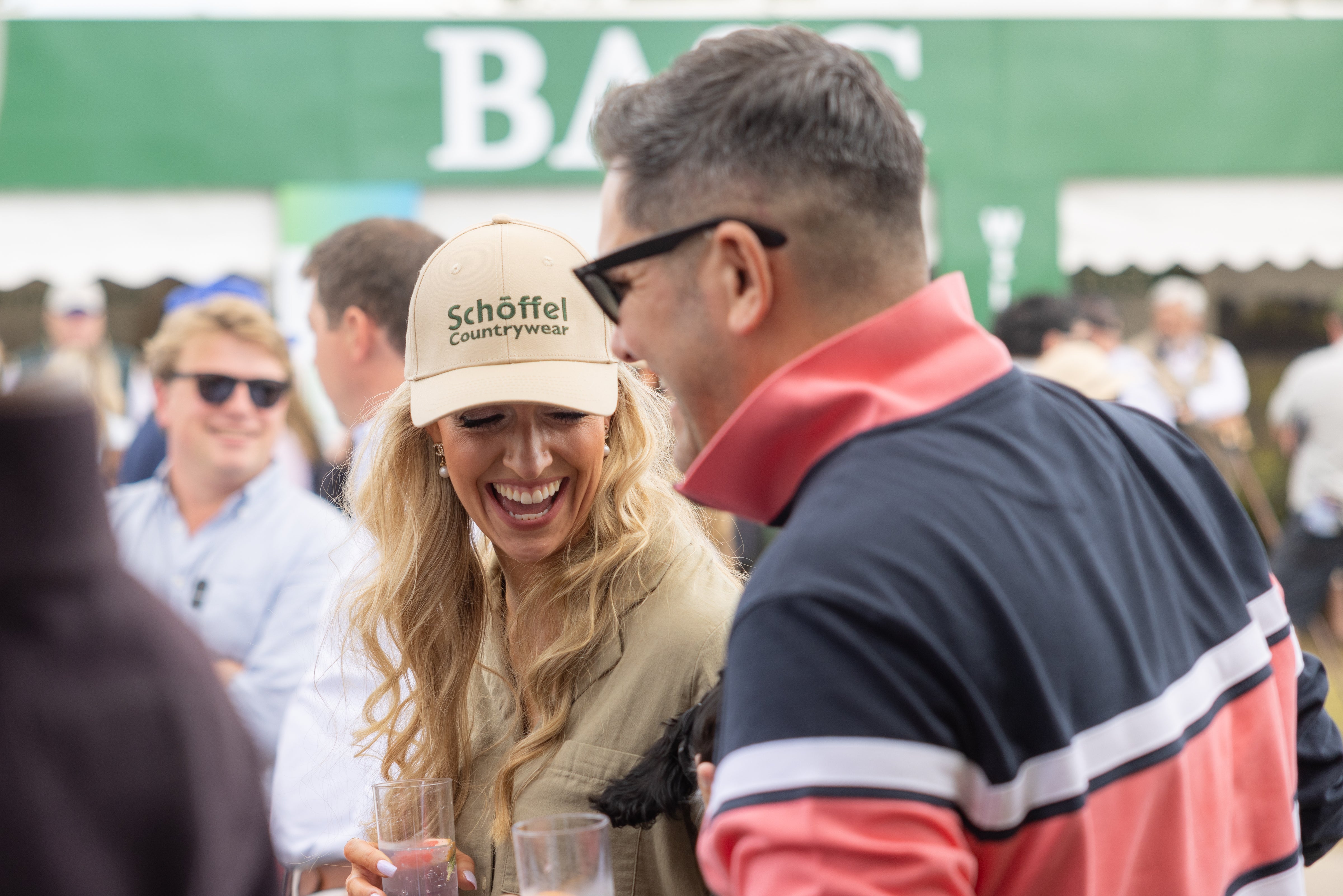 Woman wearing a Schöffel cap interacting with a man at the Game Fair