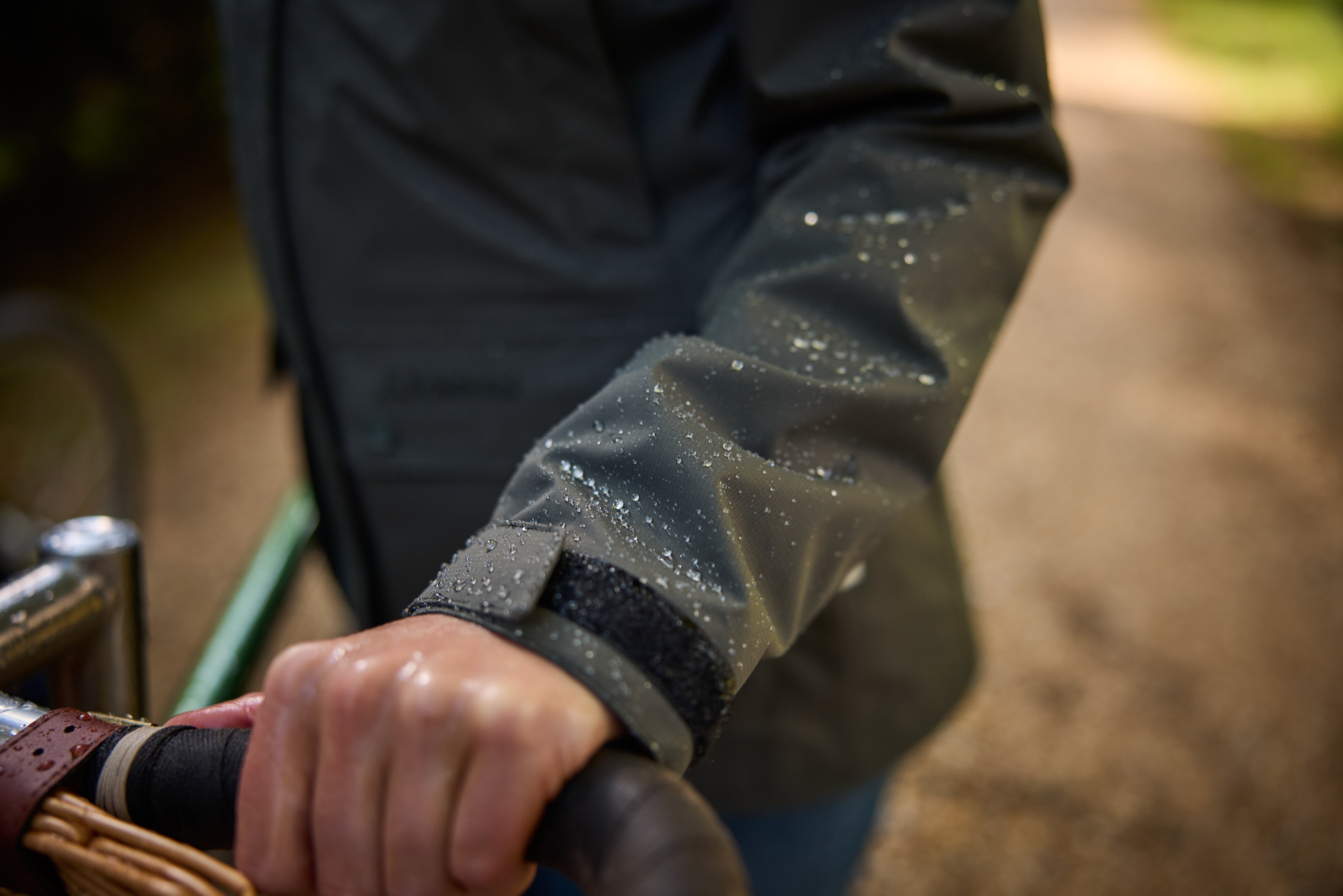 Person wearing a raincoat with water droplets on the sleeve, holding a basket.