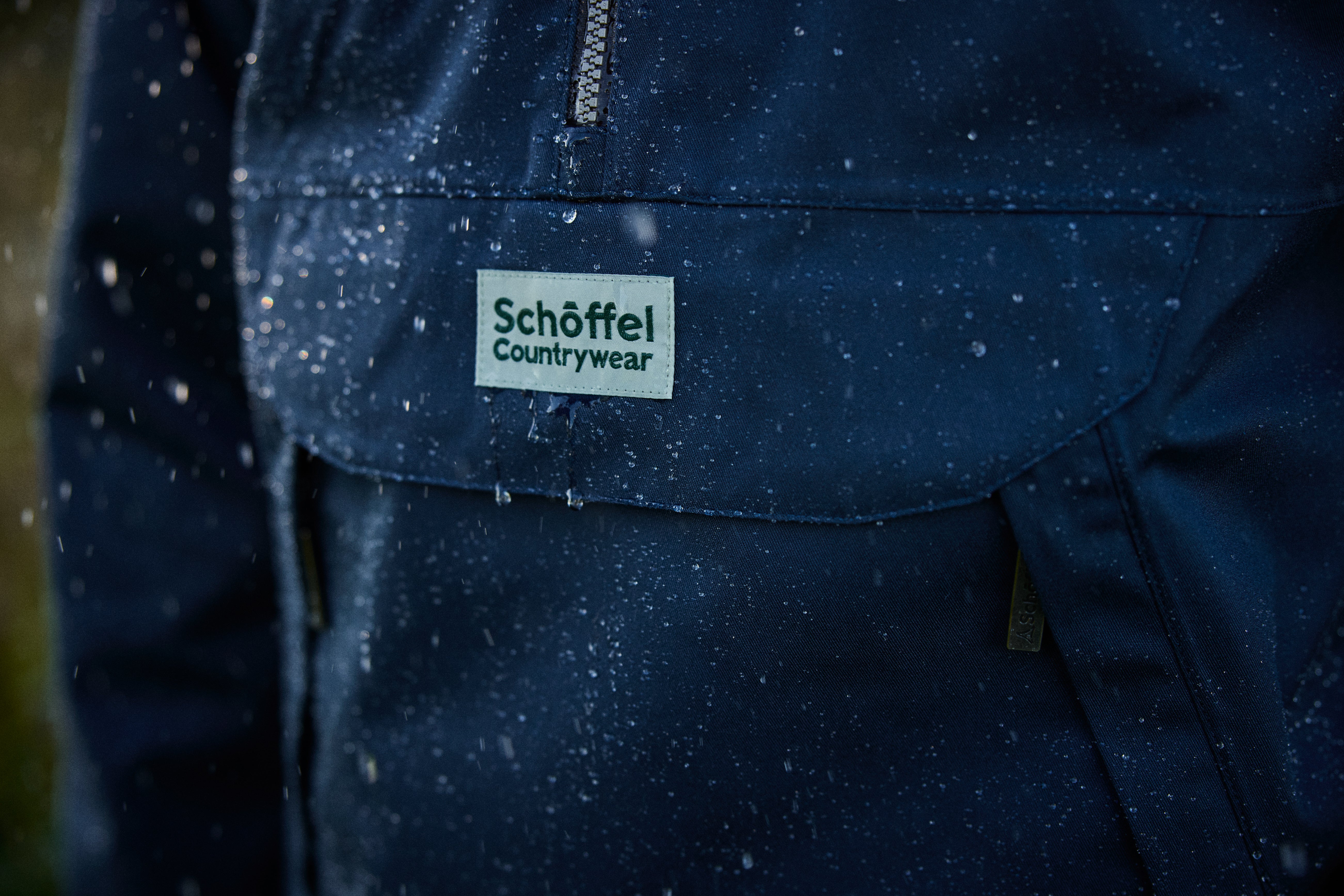 Close-up of a blue jacket with Schoffel Countrywear label in a snowy setting