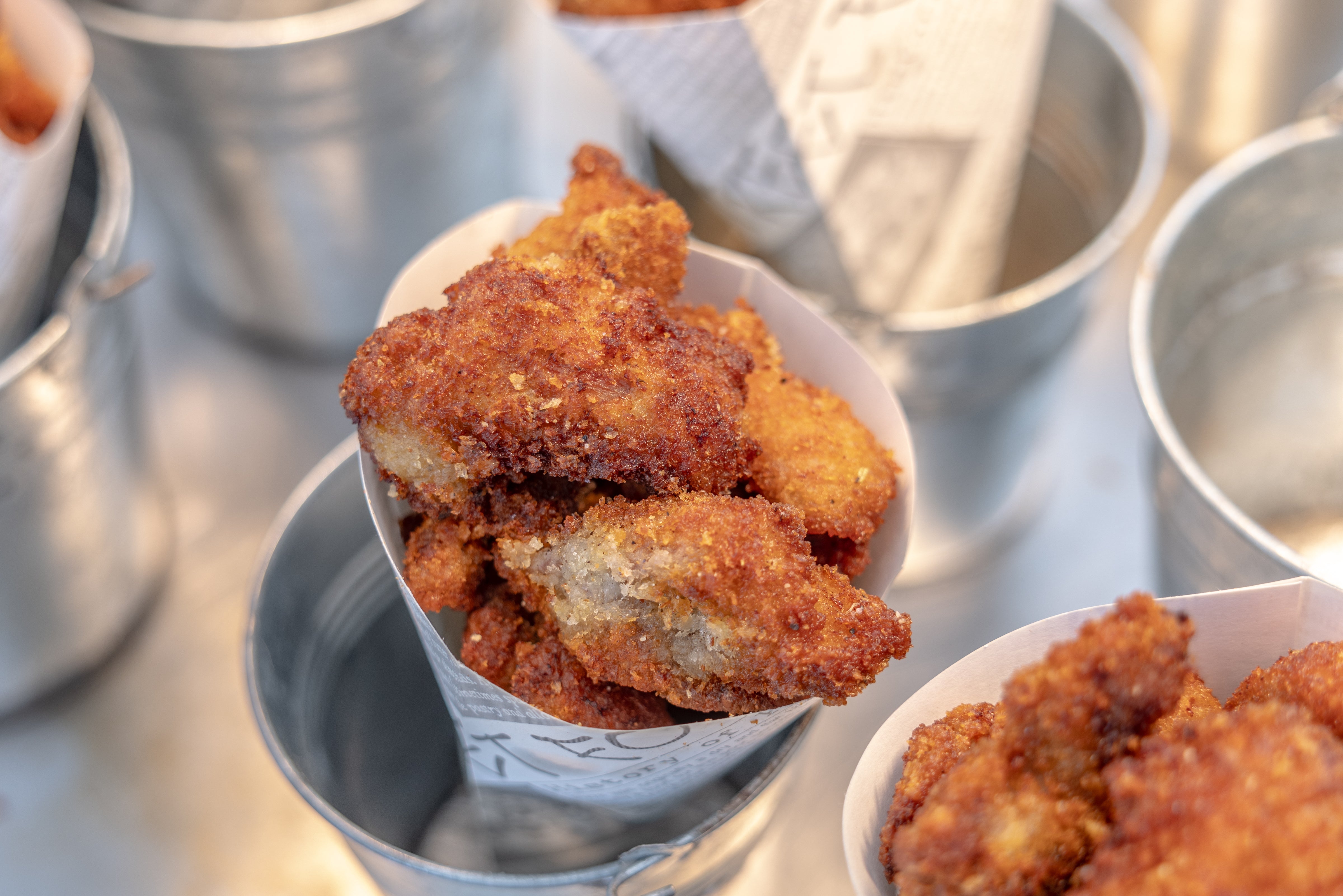 Breaded and fried food in small metal buckets.