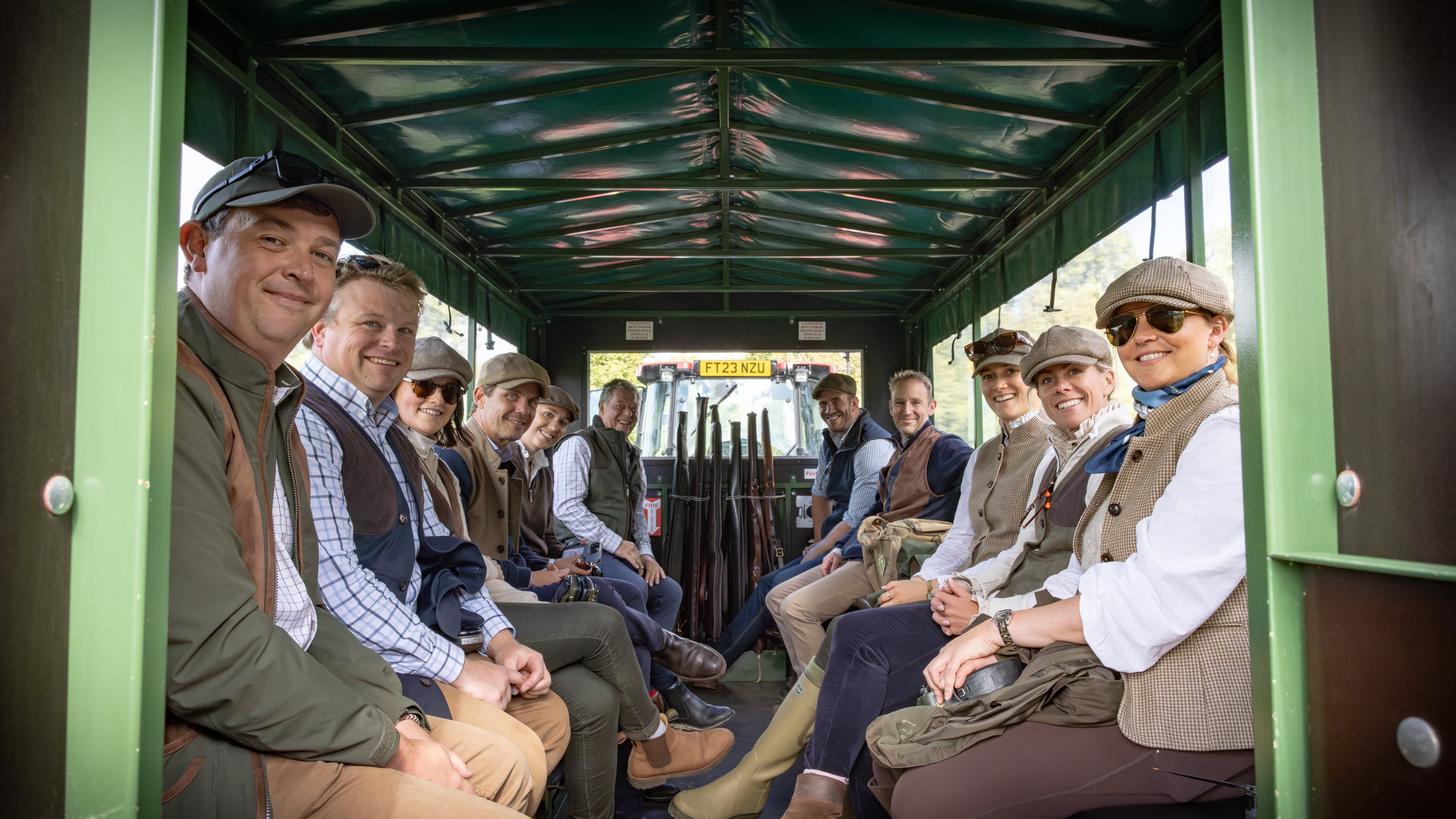 Group of people sitting inside a green vehicle, possibly a bus.