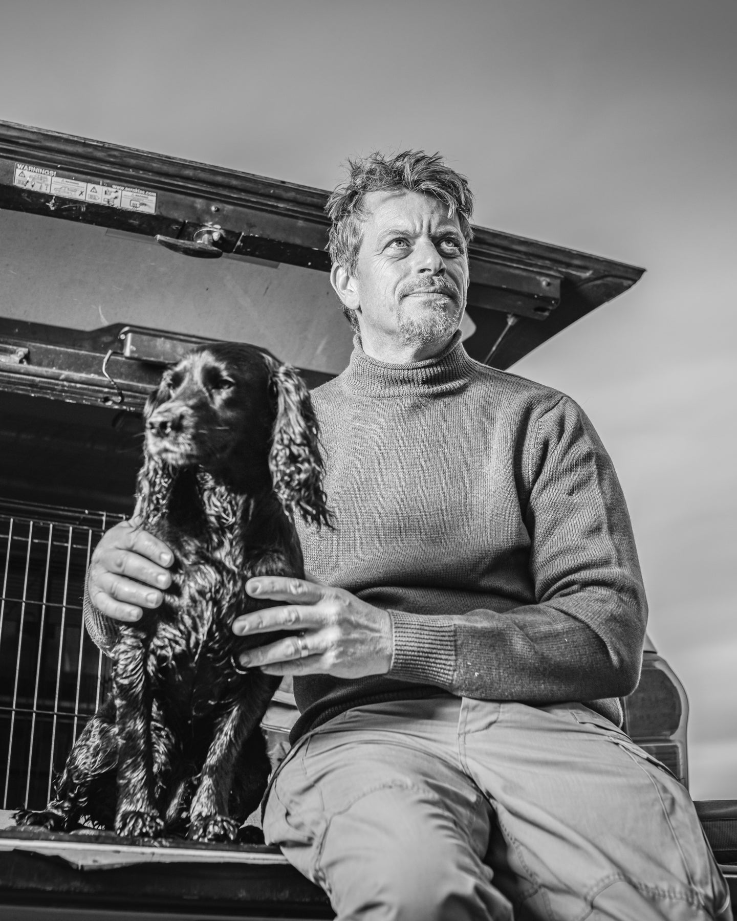 Richard Negus holding a dog in front of an open car trunk