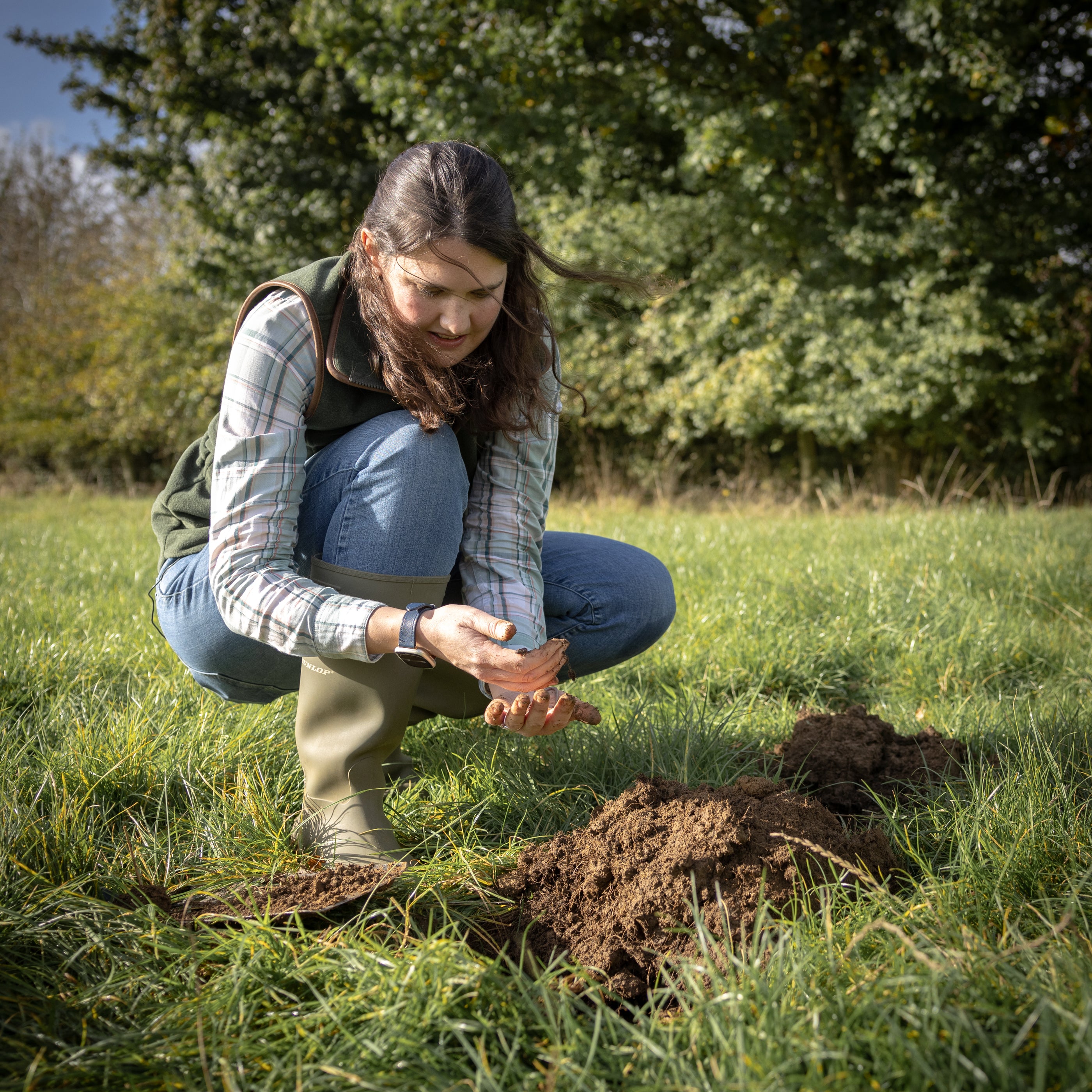 Woman in a field examining soil in her hands