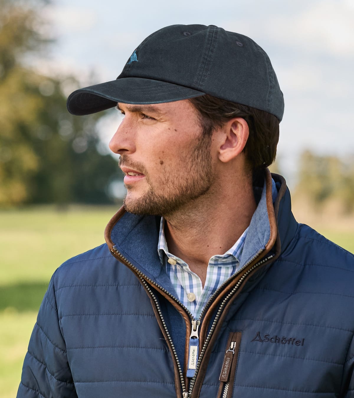Man wearing navy blue Schoffel quilted jacket and a dark navy baseball cap