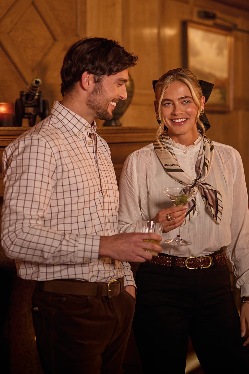 A man and a woman in a warmly lit lounge setting.