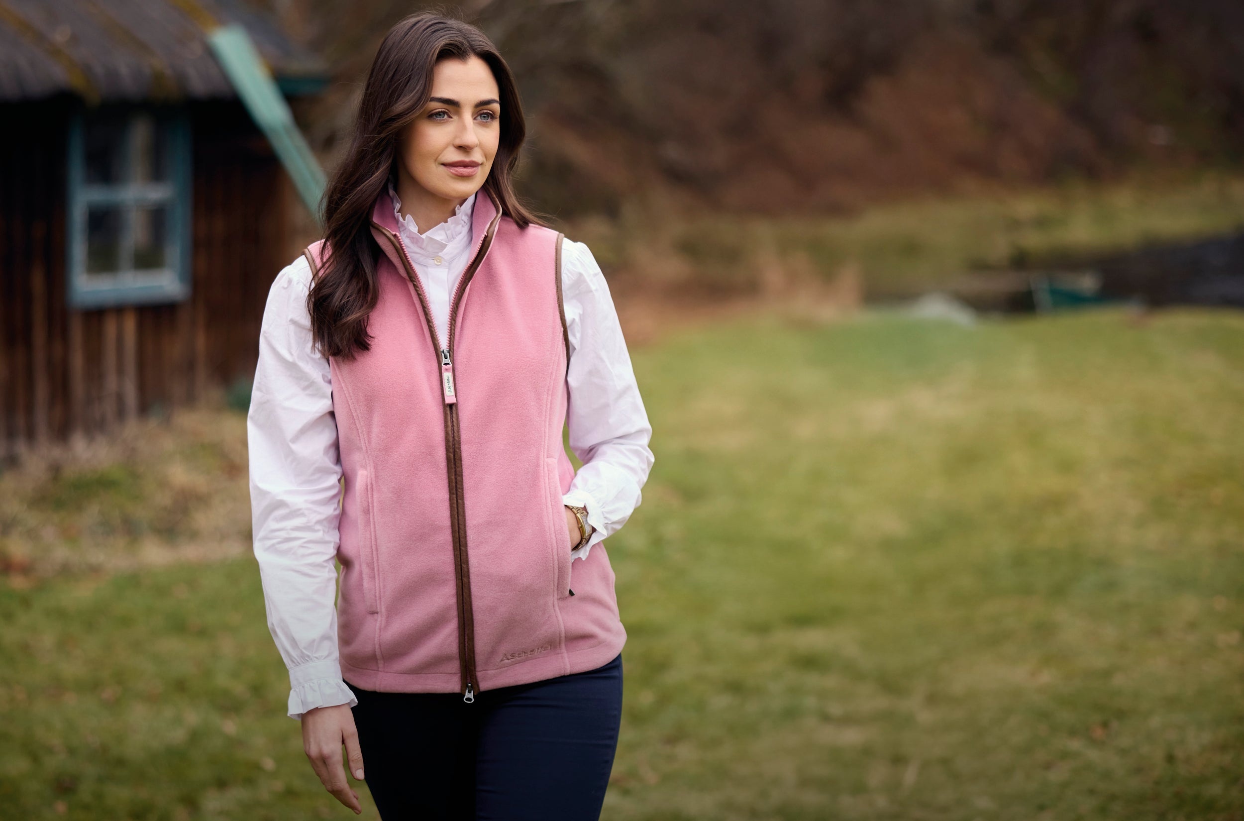 Woman wearing a pink vest over a white shirt in an outdoor setting