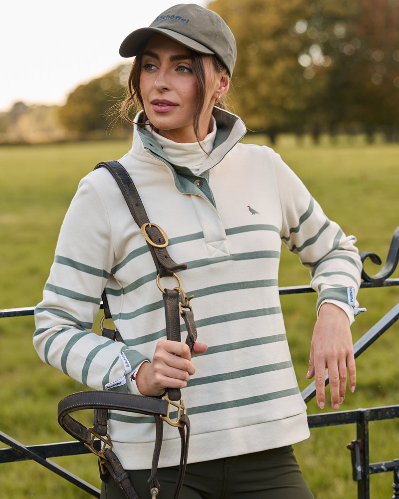 Woman wearing a striped sweater and cap in a field