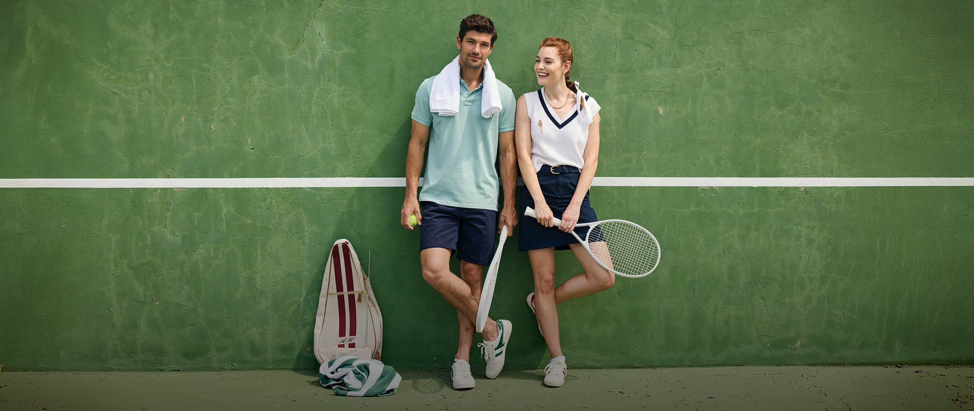 Two people on a tennis court holding tennis rackets.
