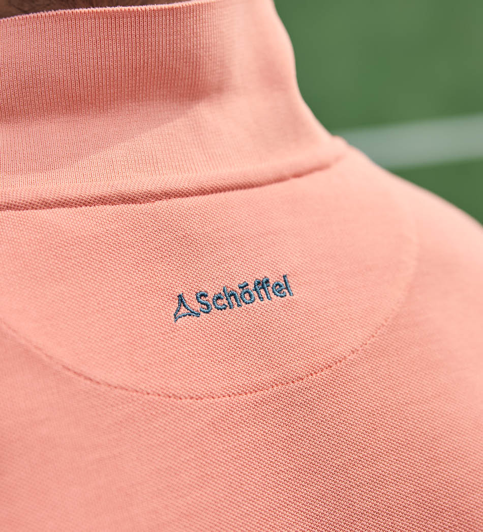Close-up of a pink garment with 'Schöffel' logo on a blurred green background