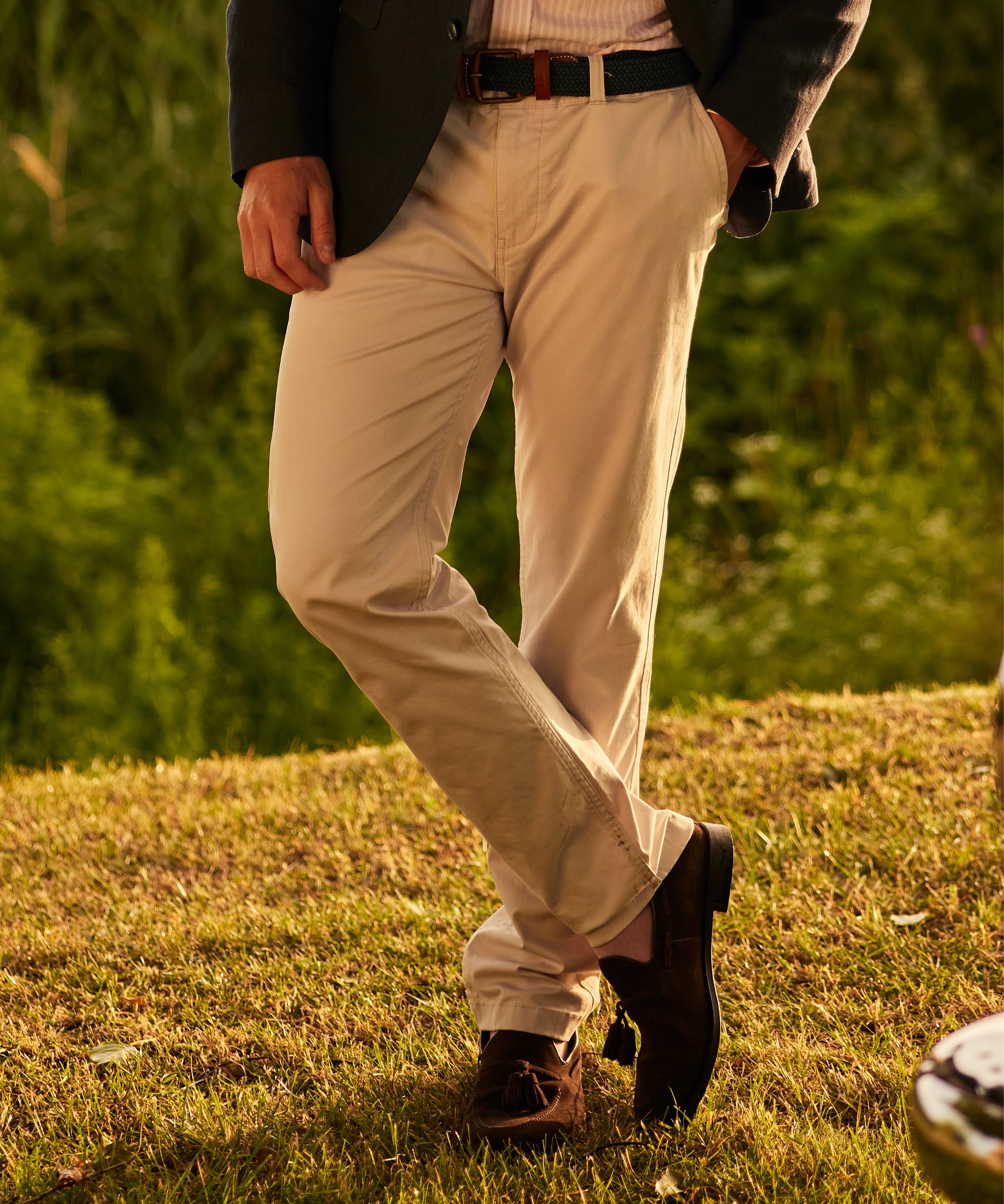 Man standing with crossed legs, wearing cream chinos.