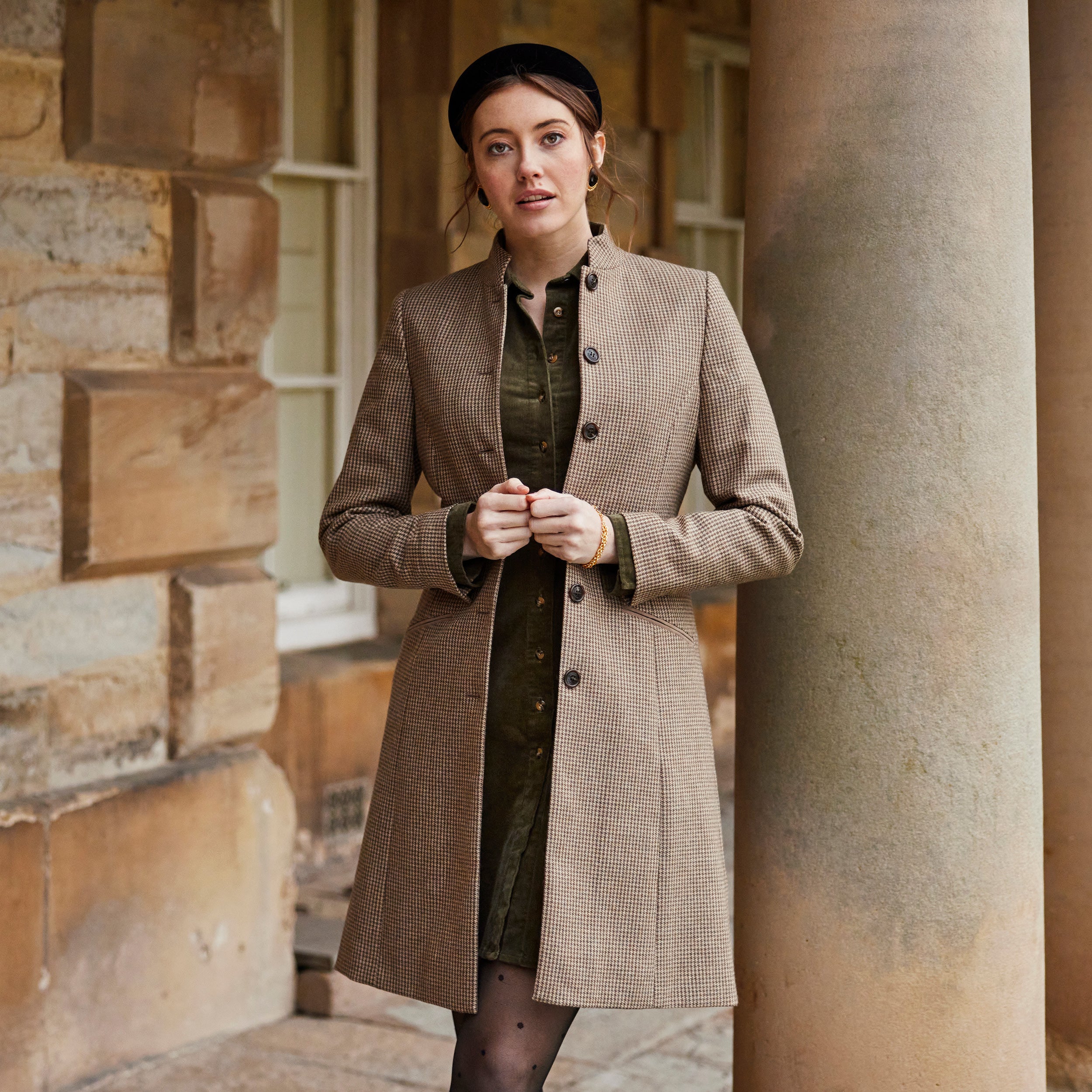 A lady wearing a tweed jacket and a green button through dress, it is paired with black polka dot tights and a black headband.