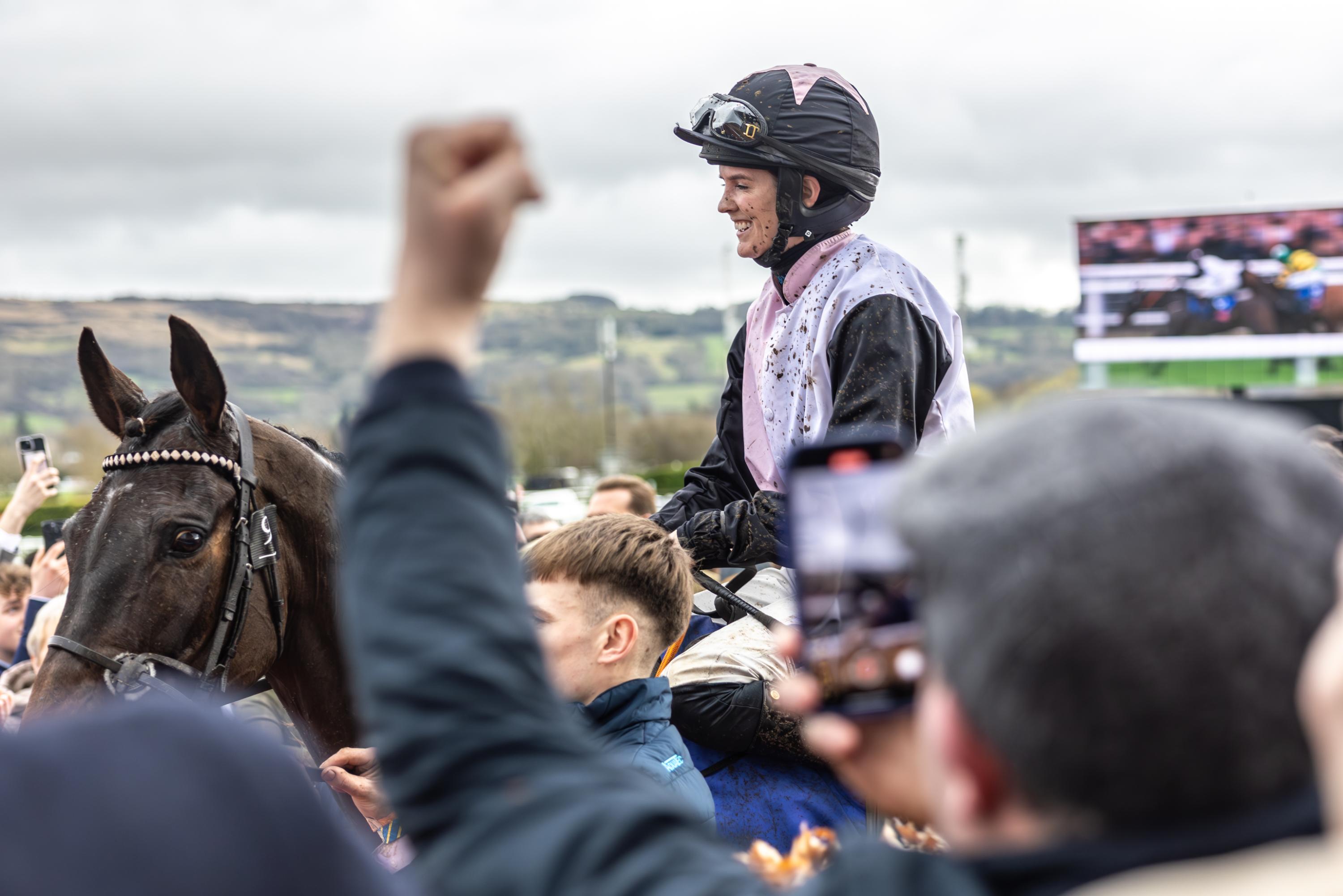 An image of a smiling jockey riding a horse.