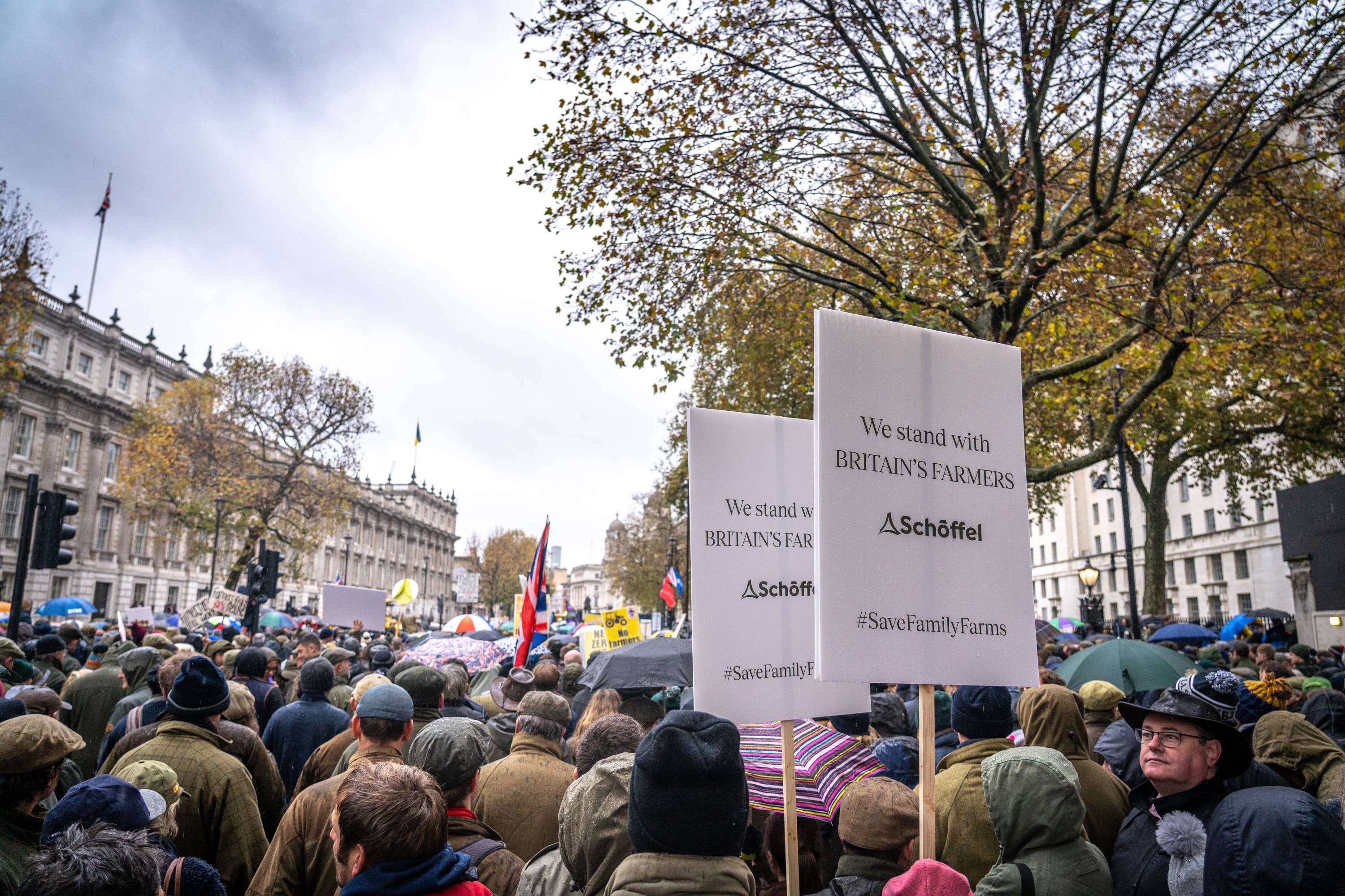 A crowd of people walking through a city holding up signs.