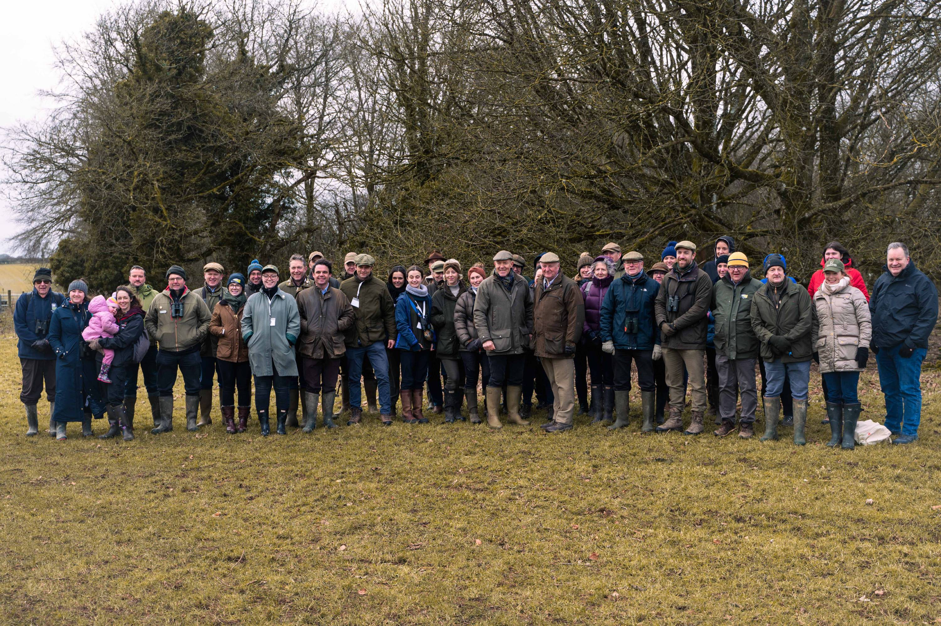 A group of people wearing winter clothing standing in a field.