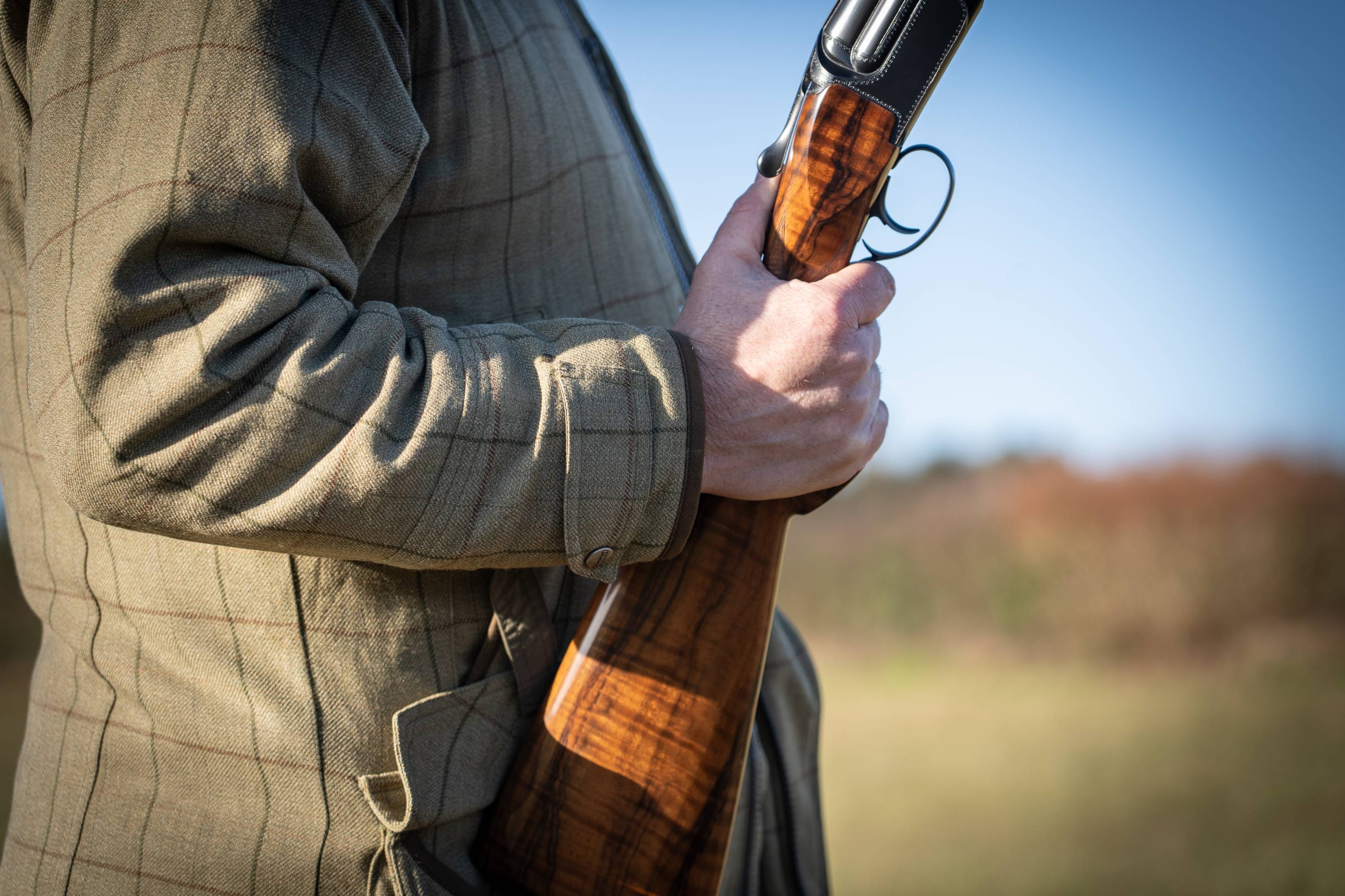 A man wearing a tweed jacket and holding a gun.