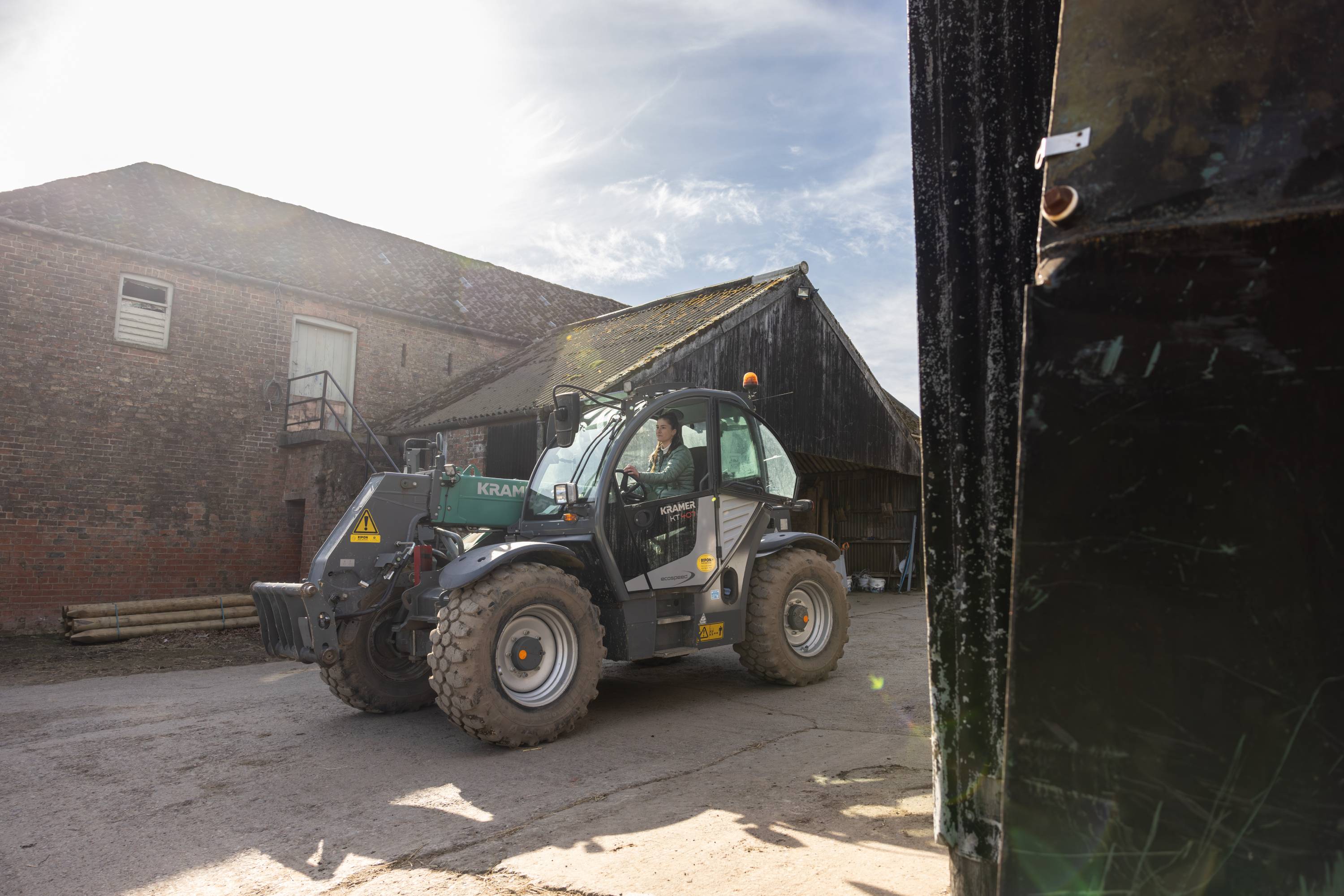 An image of a woman driving a tractor in a farm yard.