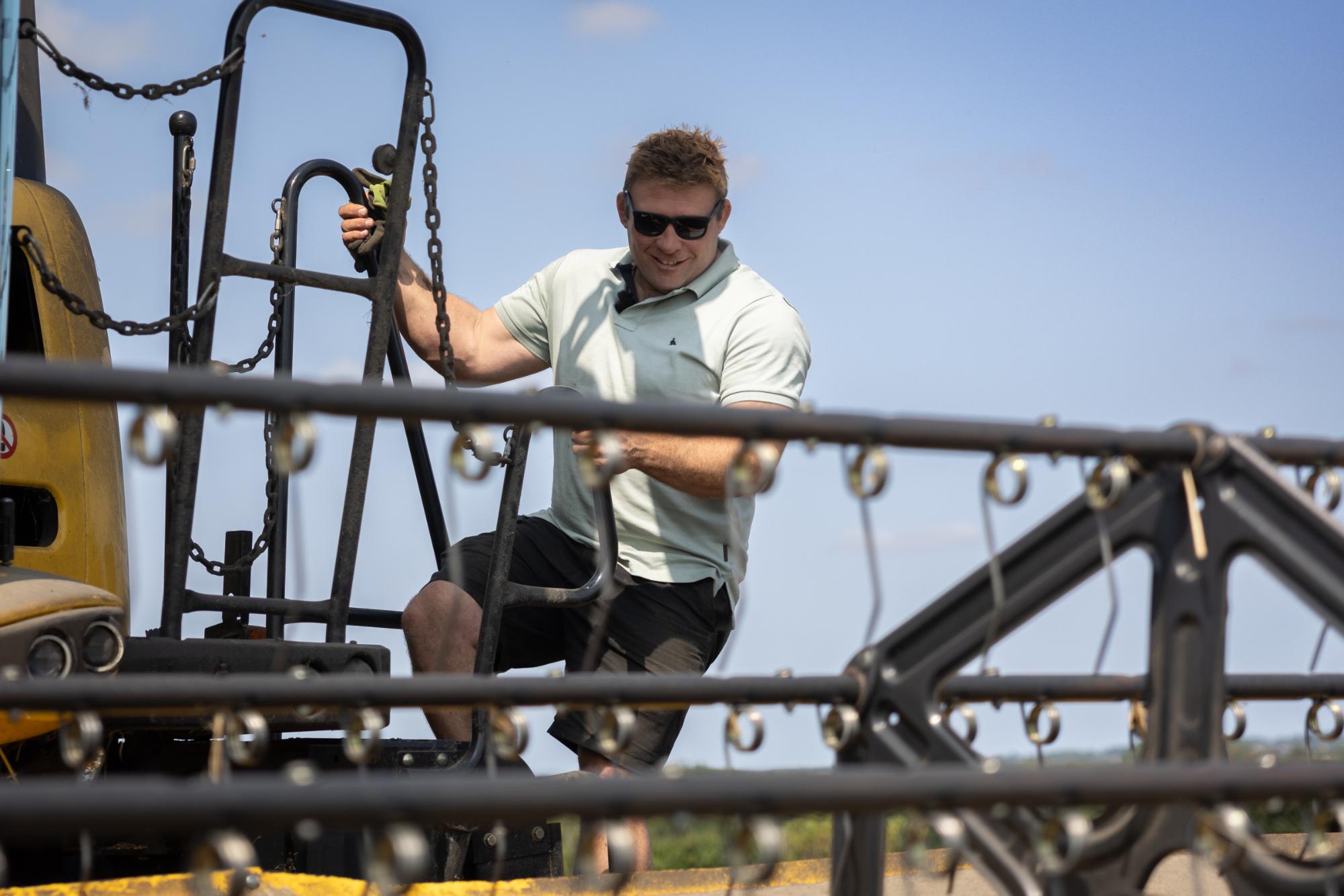 Man operating heavy machinery with a clear blue sky in the background