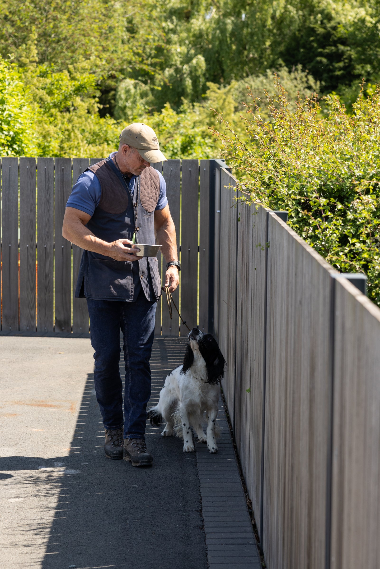 Man walking a dog on a wooden deck with greenery in the background