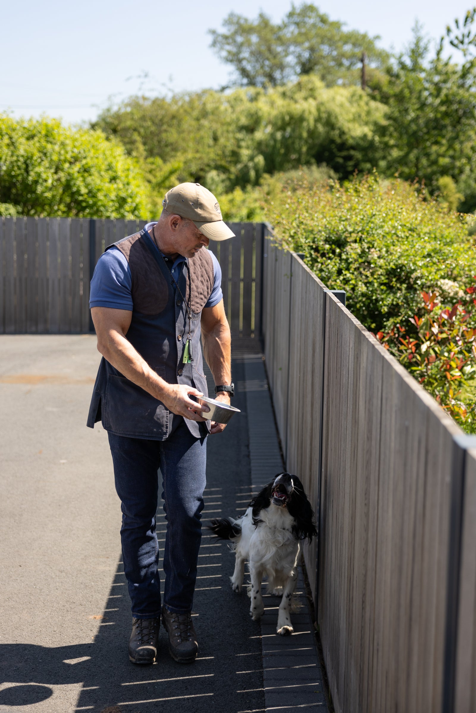 Man walking a dog on a leash in an outdoor setting with greenery.