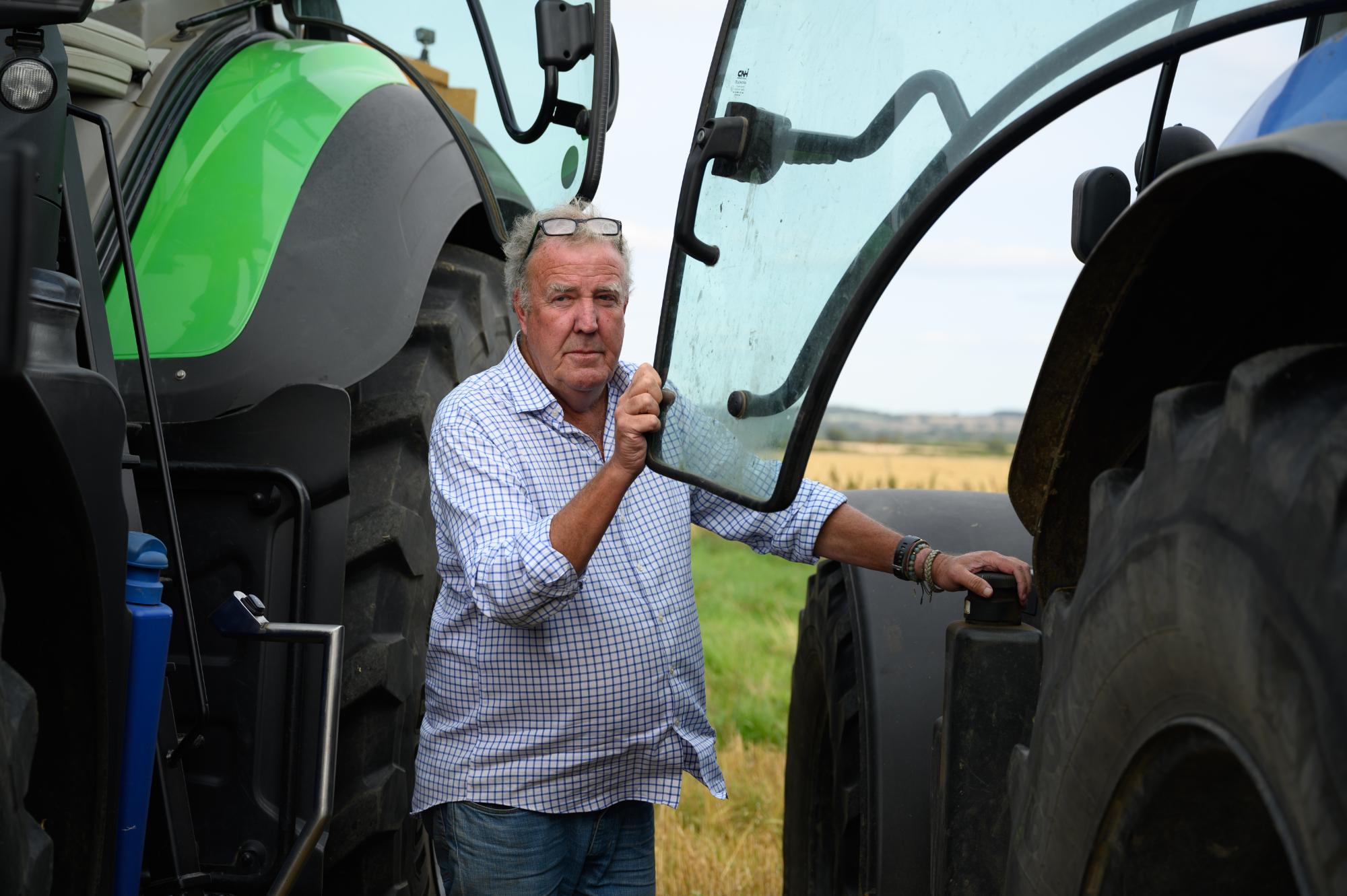 Man standing next to a large tractor in an open field