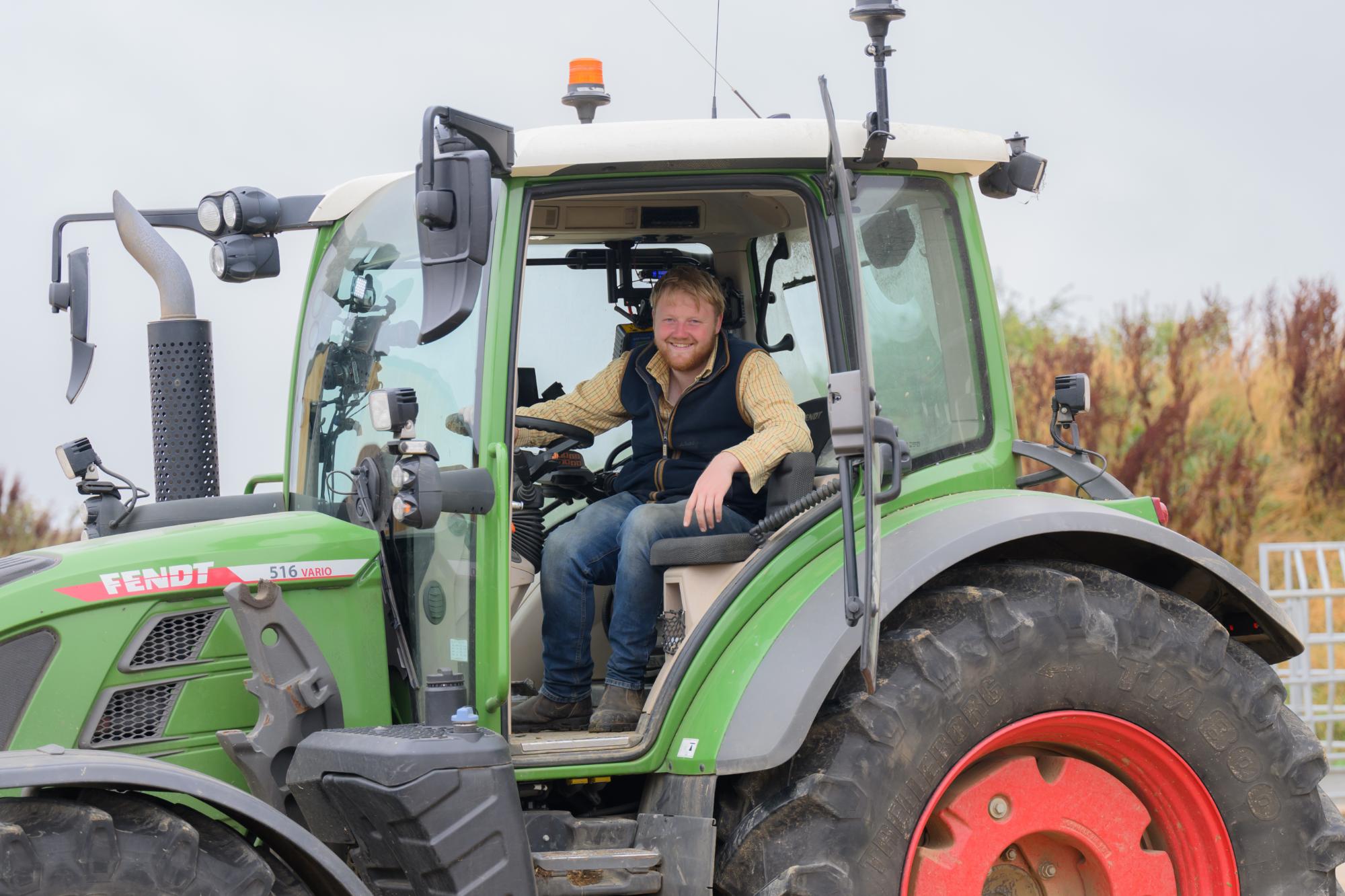 Man sitting inside a green tractor on a farm