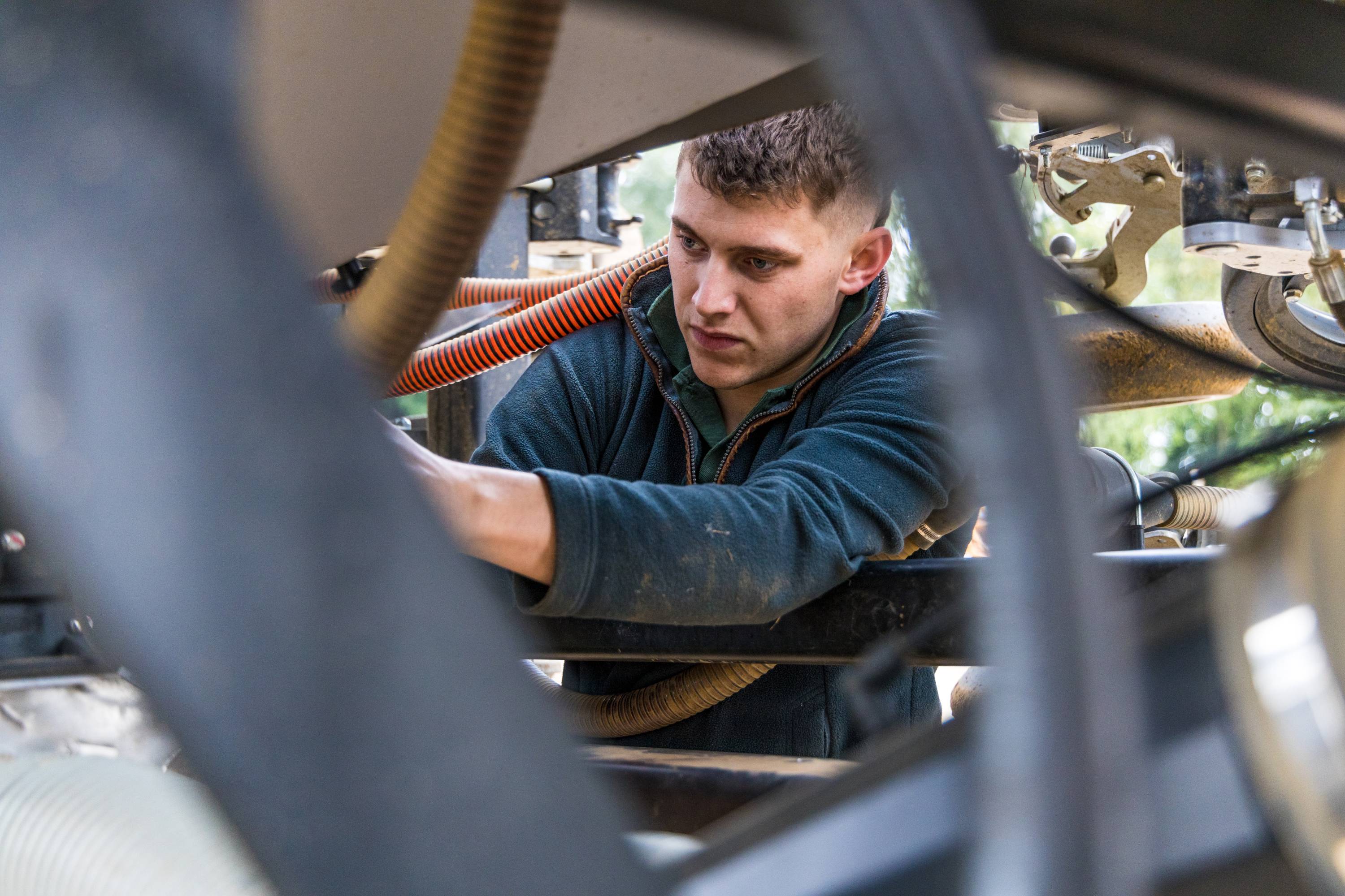 A young farmer fixing machinery.