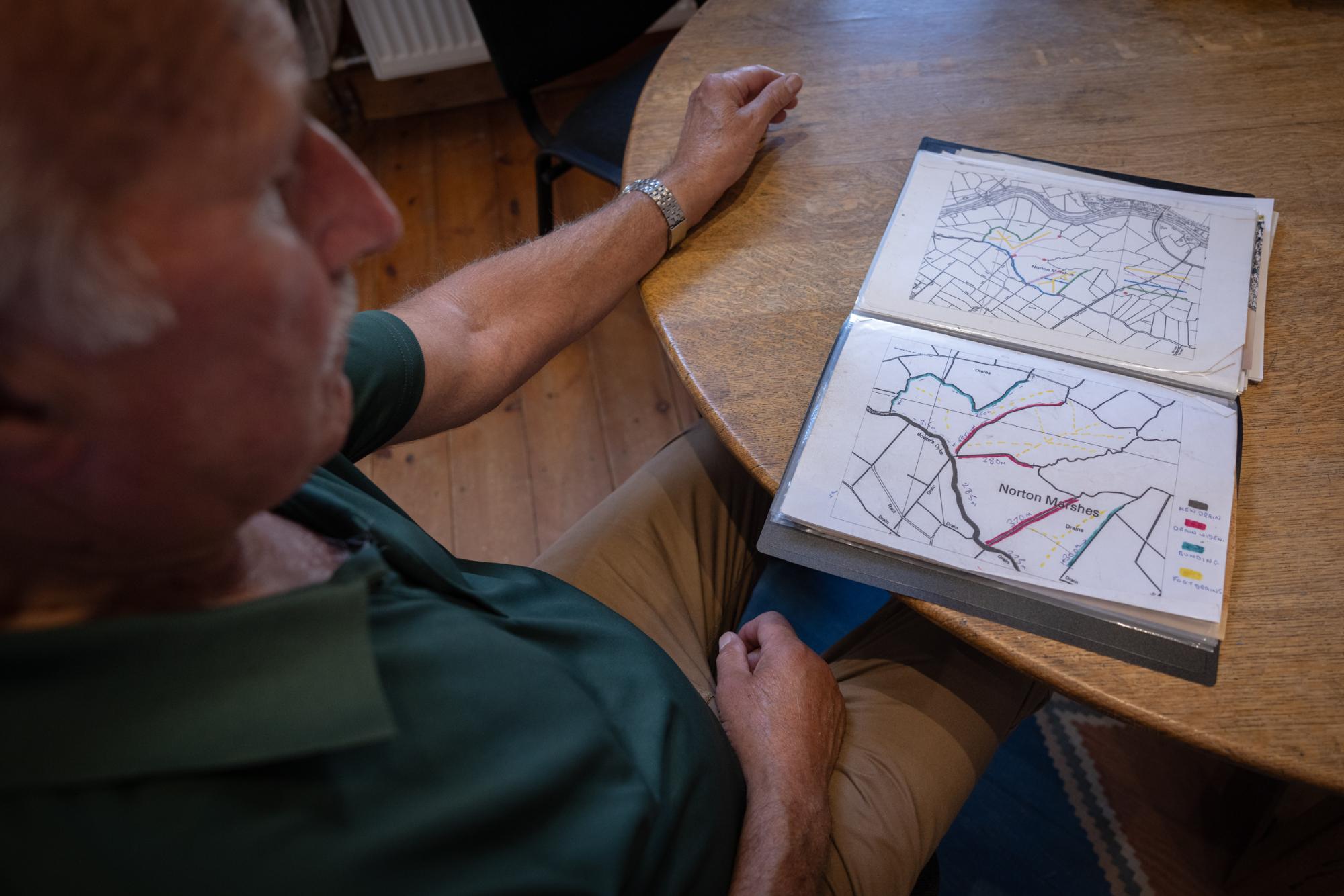 Person sitting at a table with an open book displaying maps.