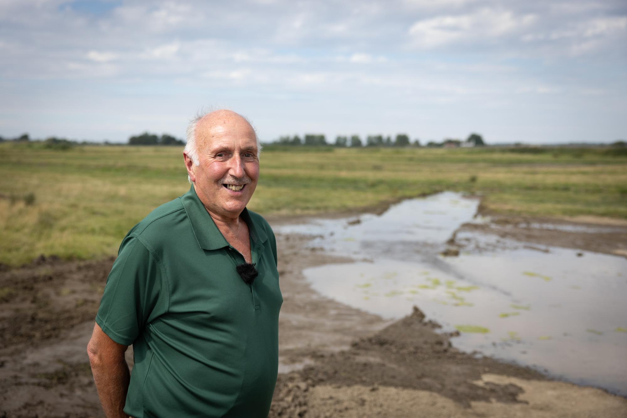 Man standing in a field with a puddle and grass in the background