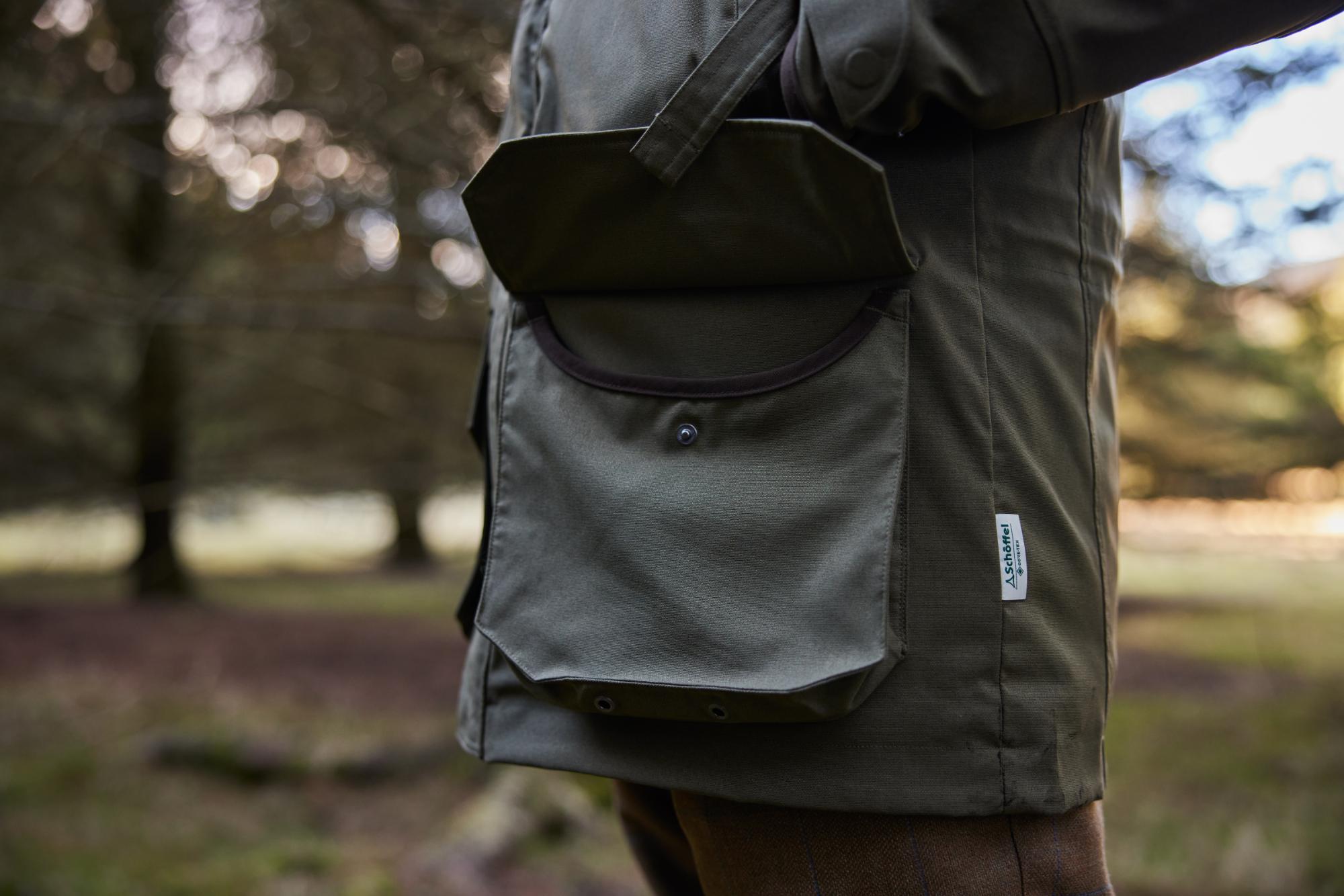 Person wearing a green jacket with a blurred natural background