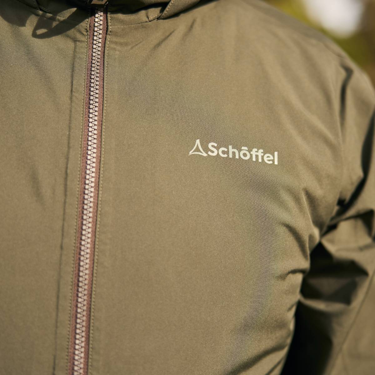 Close up of a green waterproof jacket with the Schöffel logo.