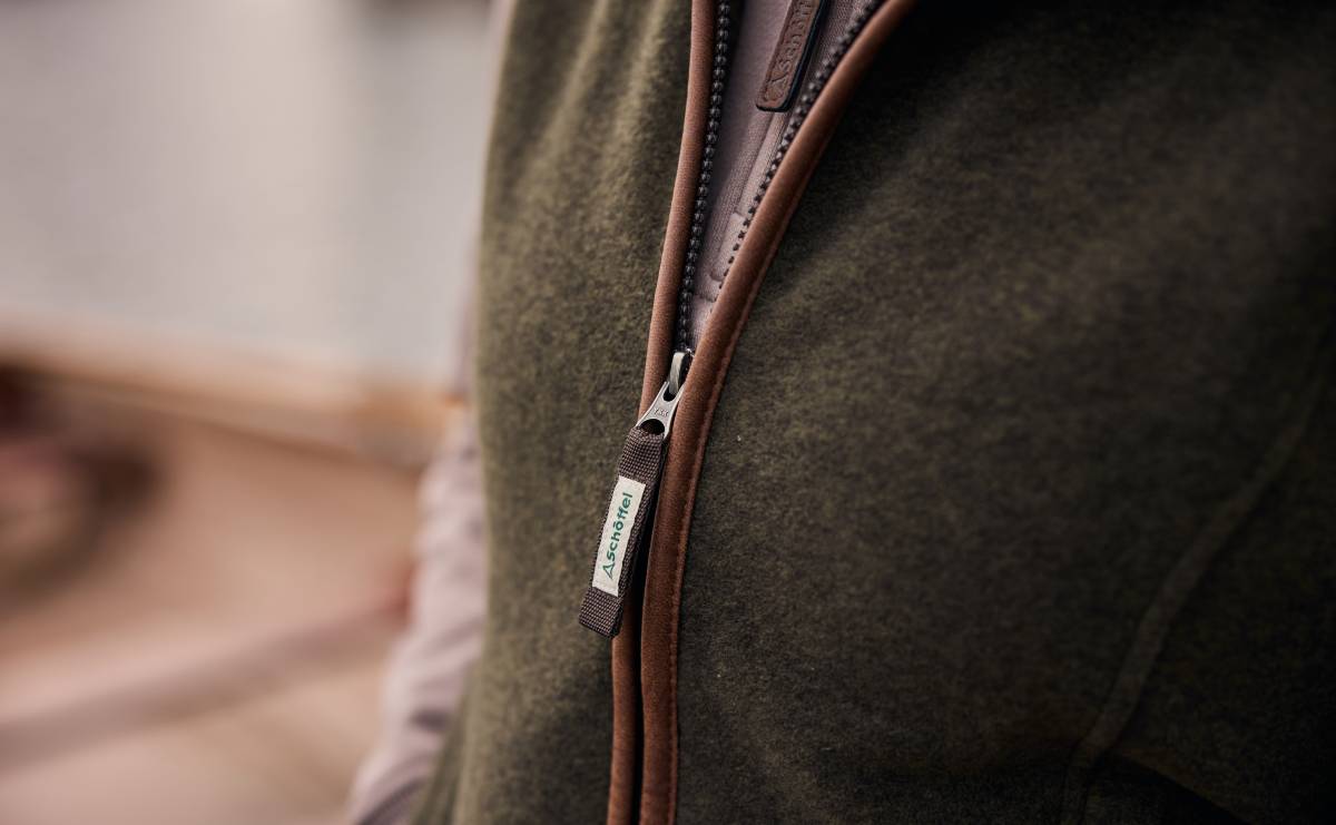 Close-up of a brown zipper on a dark green fleece gilet with a blurred background
