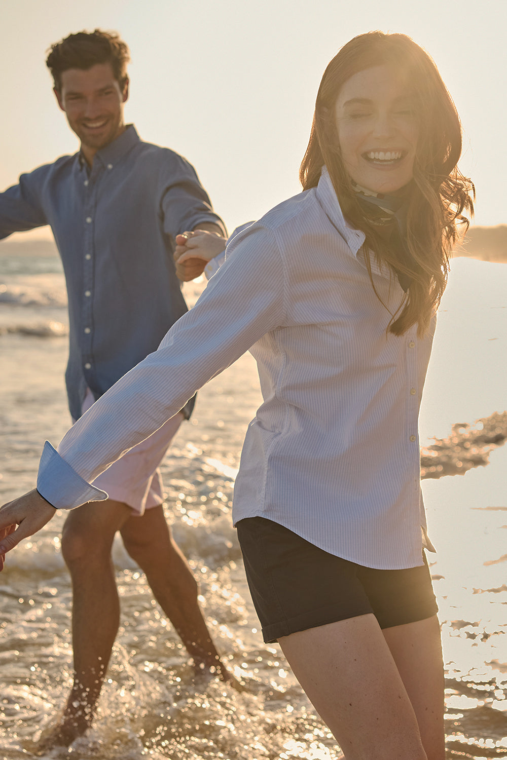 Two people on a beach with the sun setting in the background