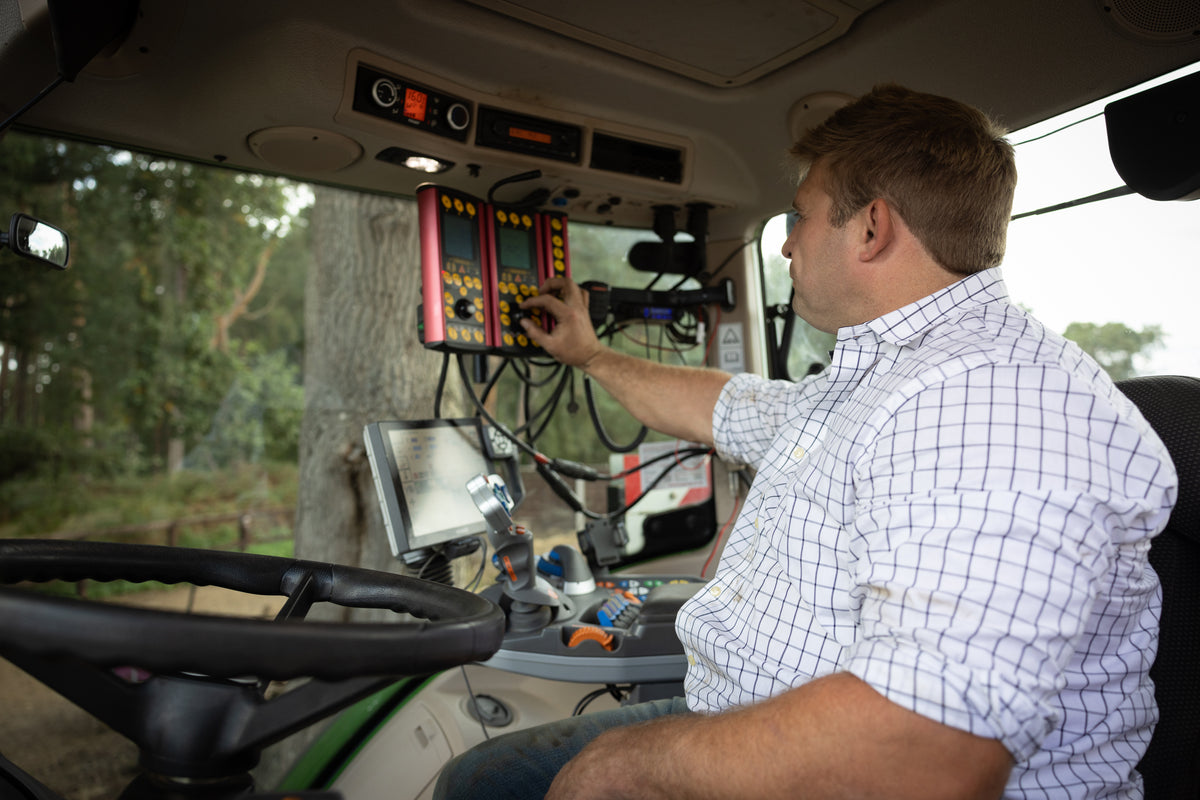 Tom Youngs in the tractor cab, adjusting the seed drill controls before heading out
