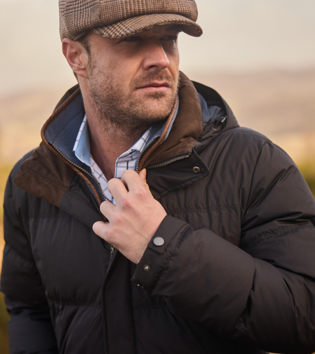 Man wearing charcoal puffer jacket with a brown suede-effect collar and zip trim