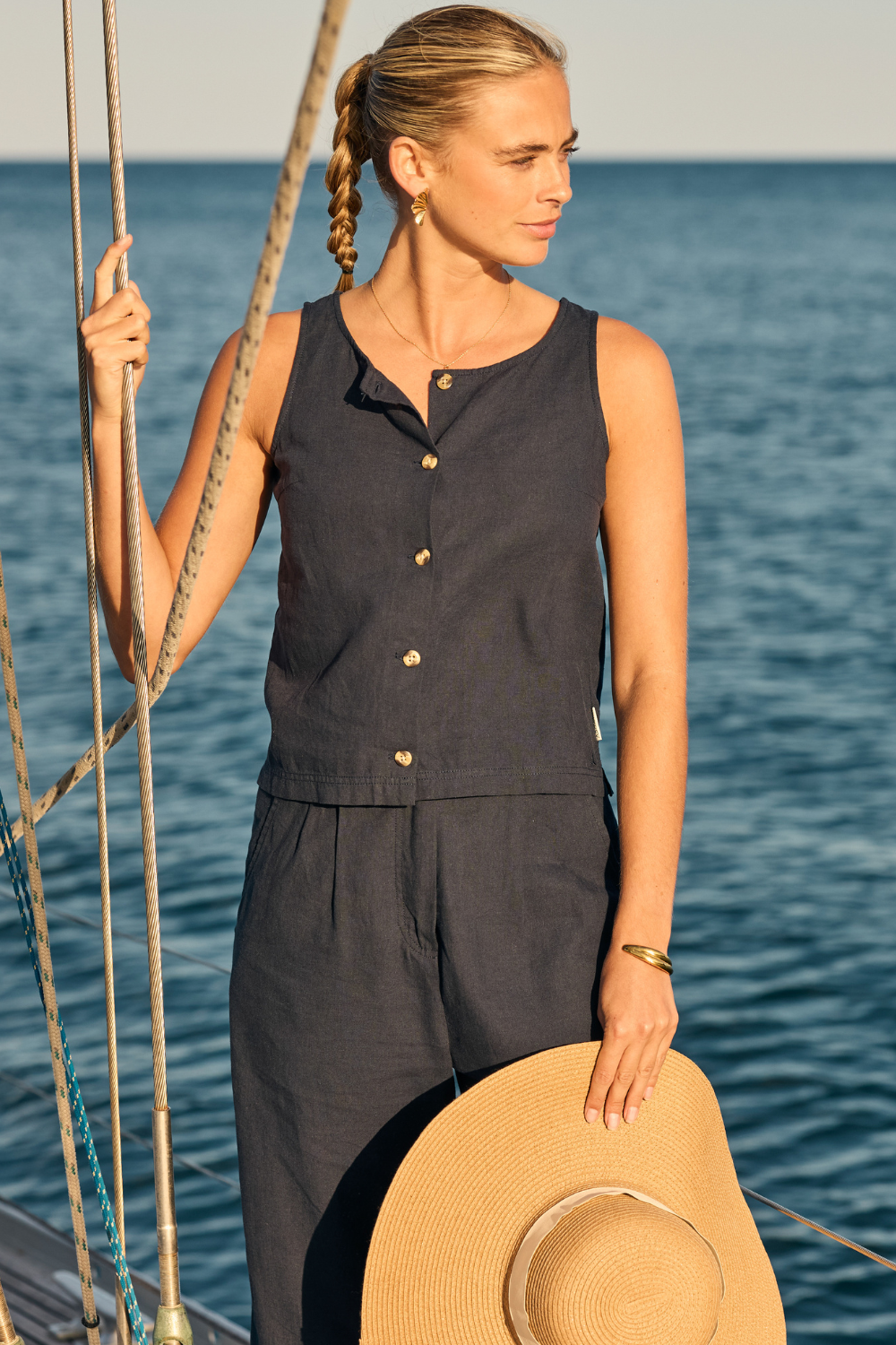 Woman in a dark sleeveless outfit standing on a boat with water in the background