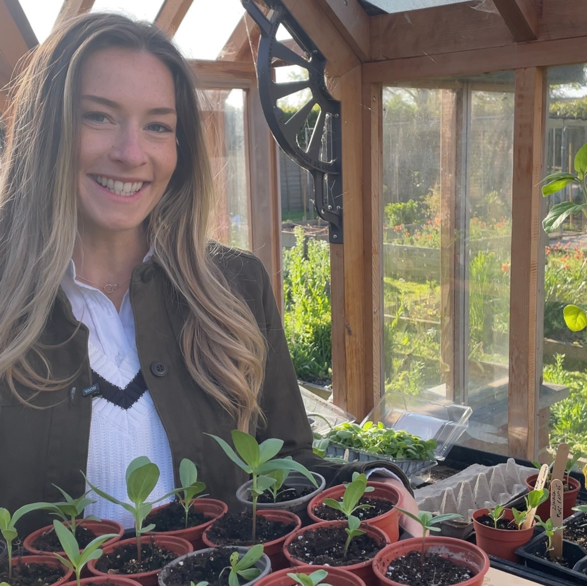 Woman standing in a greenhouse with seedlings in pots