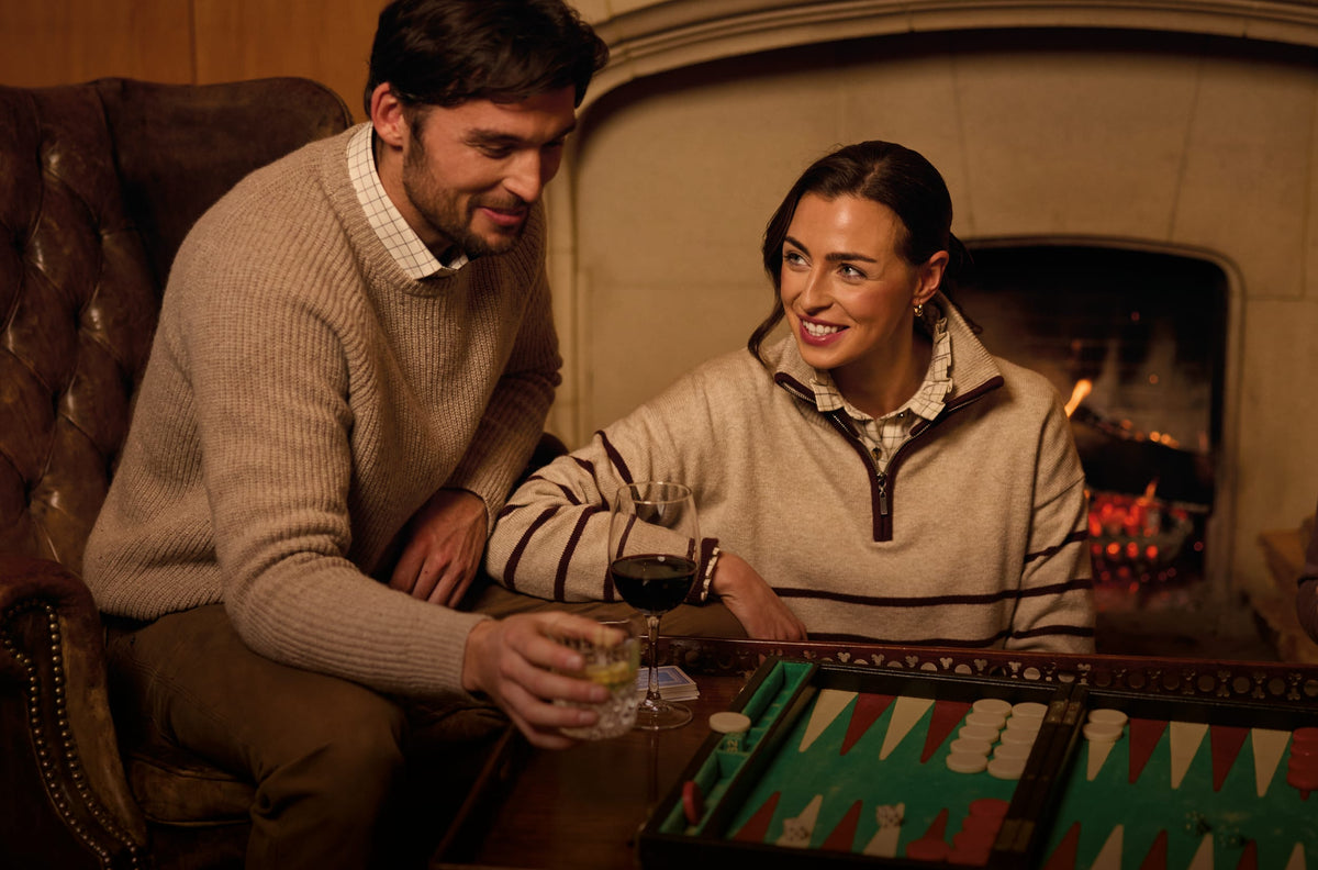 Man and woman sitting by a fire playing a board game