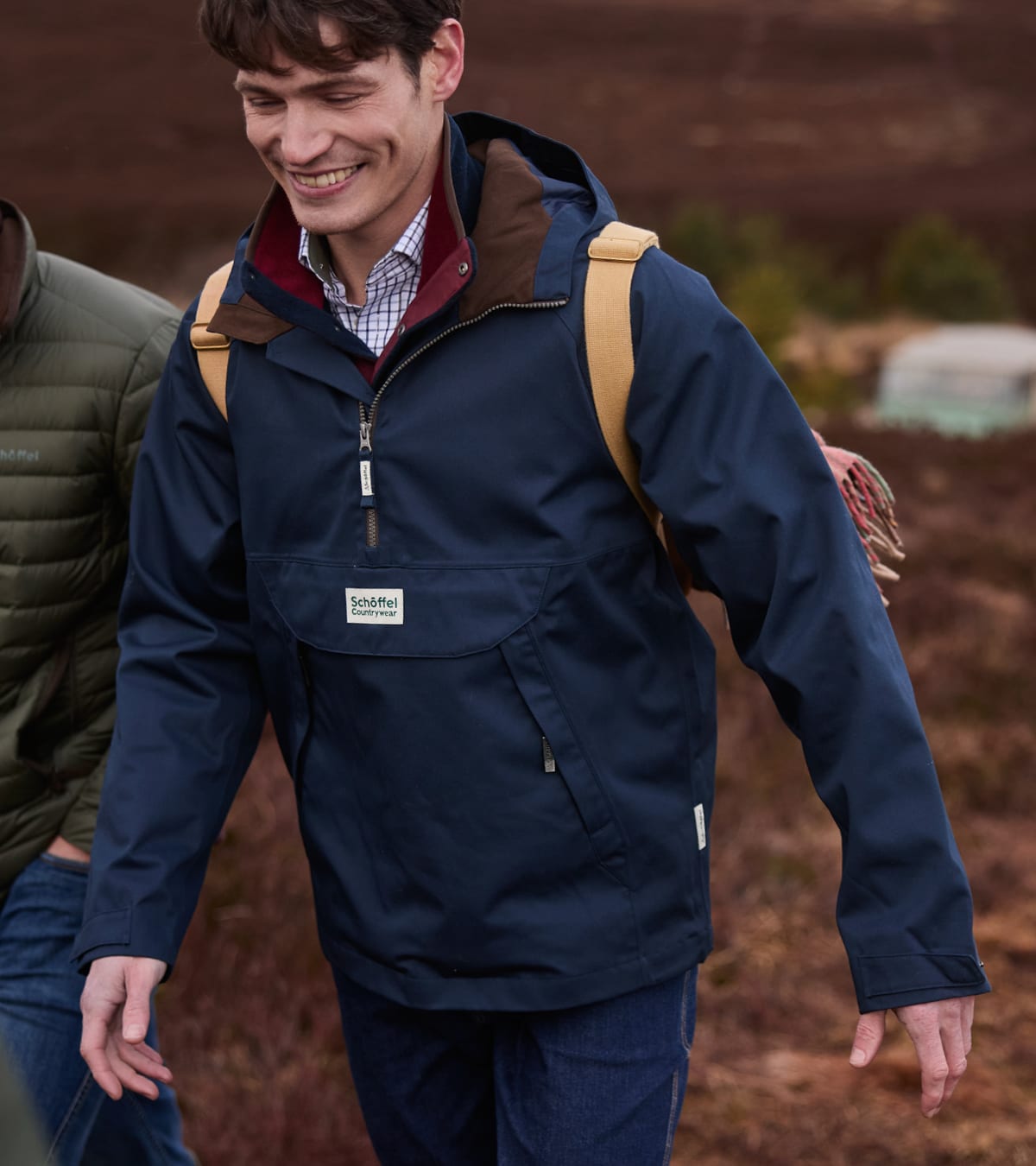 Man walking across moorland wearing a navy overhead smock jacket and rucksack