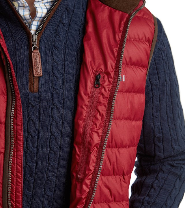 Detail of Schöffel Men's Bowden Down Gilet in red showing the inner chest zip pocket alongside a navy cable-knit layer, with a Schöffel branded leather zip pull